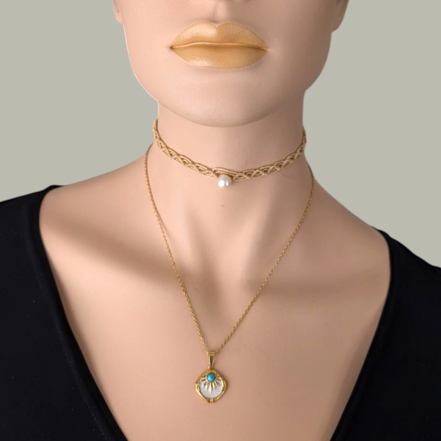 Western sunburst white enamel gold stainless steel necklace layered with a macrame pearl choker, on mannequin close up bust view
