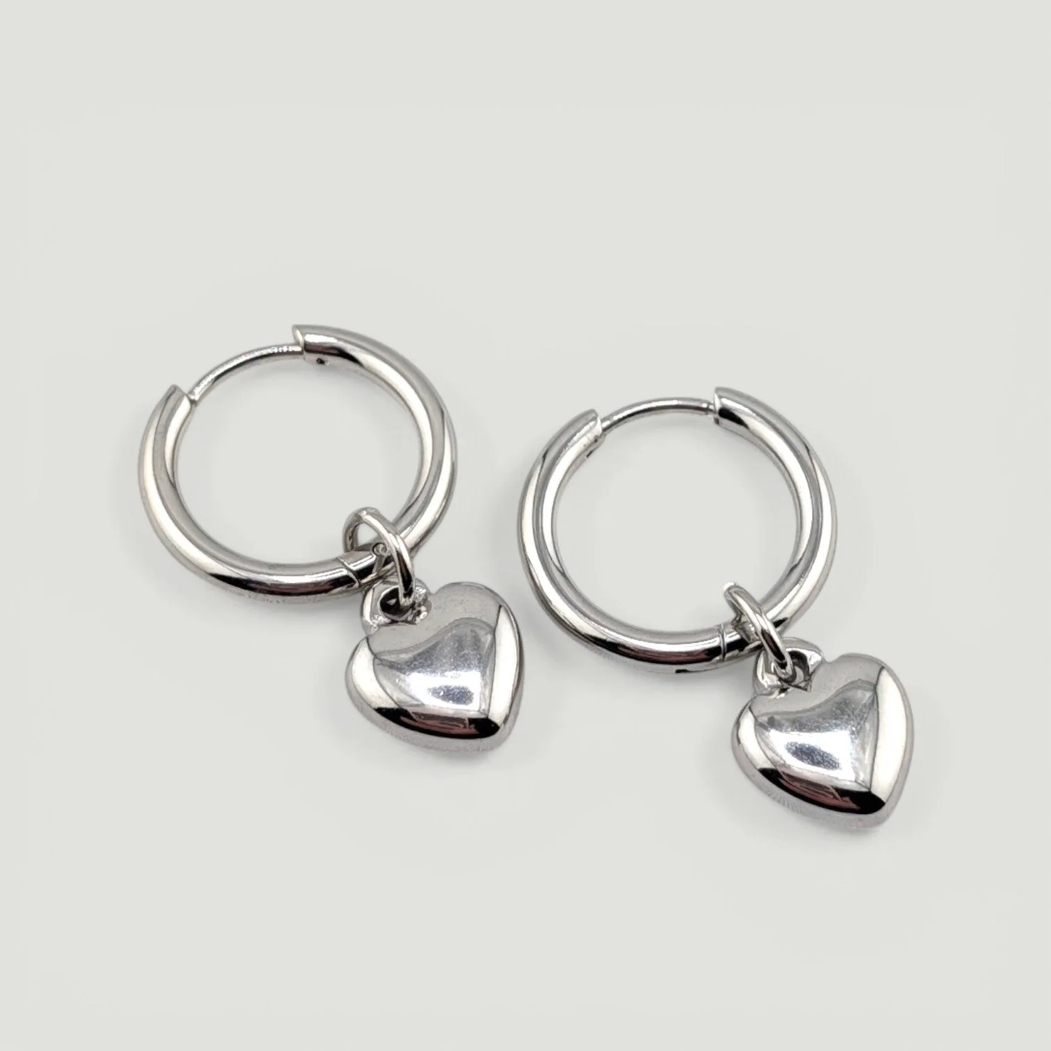 silver puffy heart huggie hoops earrings, flat lay