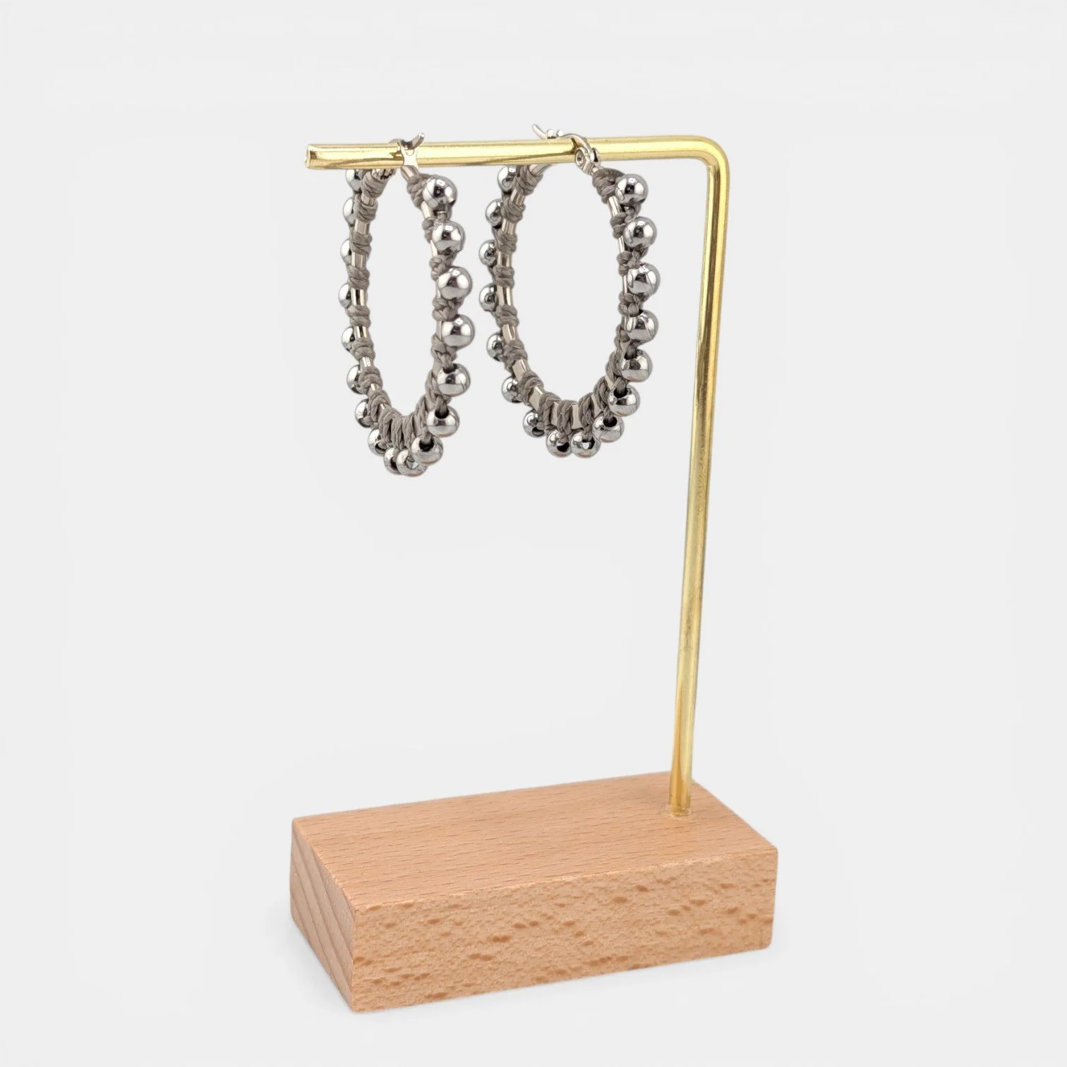 Light gray beaded macramé stainless steel hoop earrings in silver, 40 mm drop shown on earring display stand