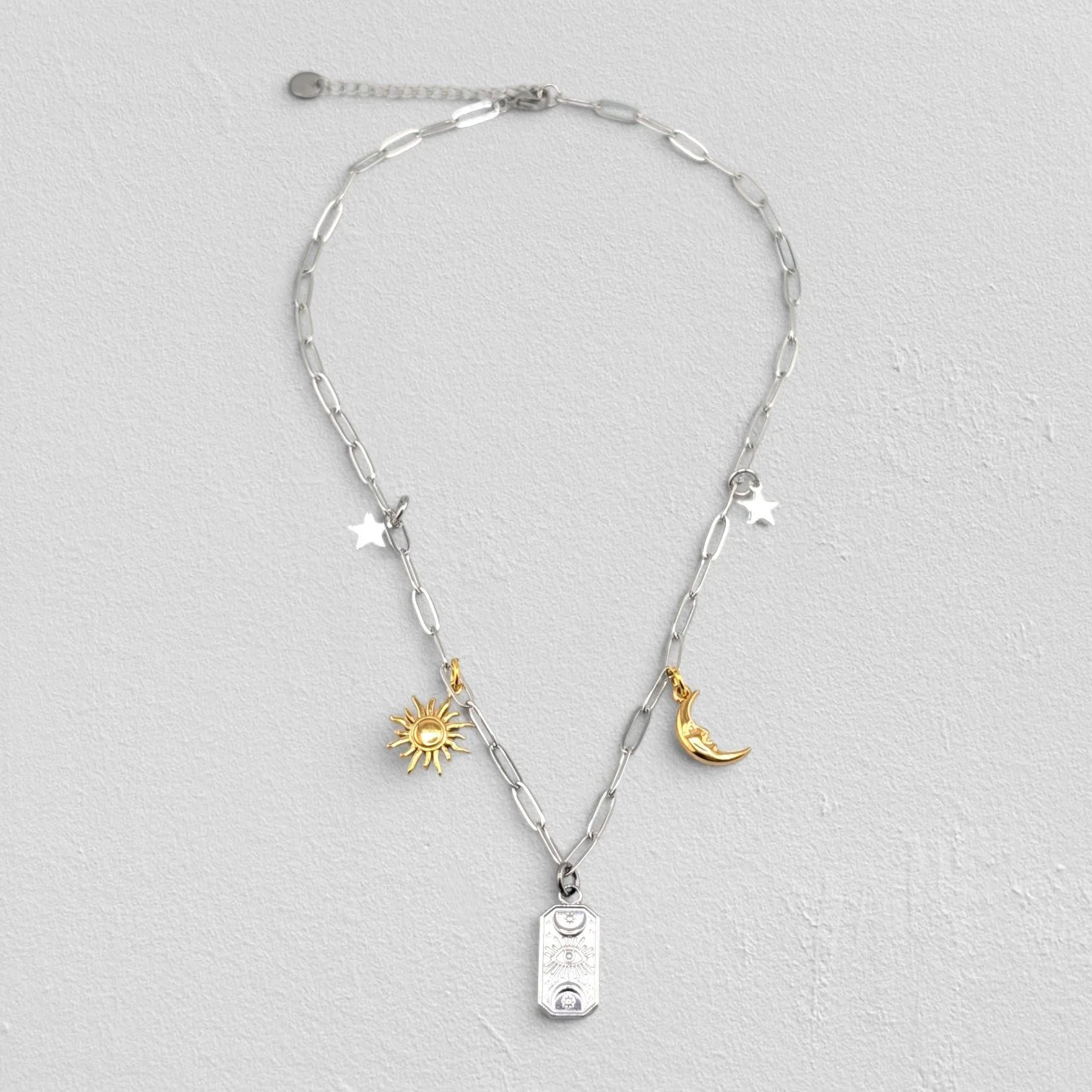 Silver two-tone evil eye celestial stainless steel charm necklace full view flat lay.