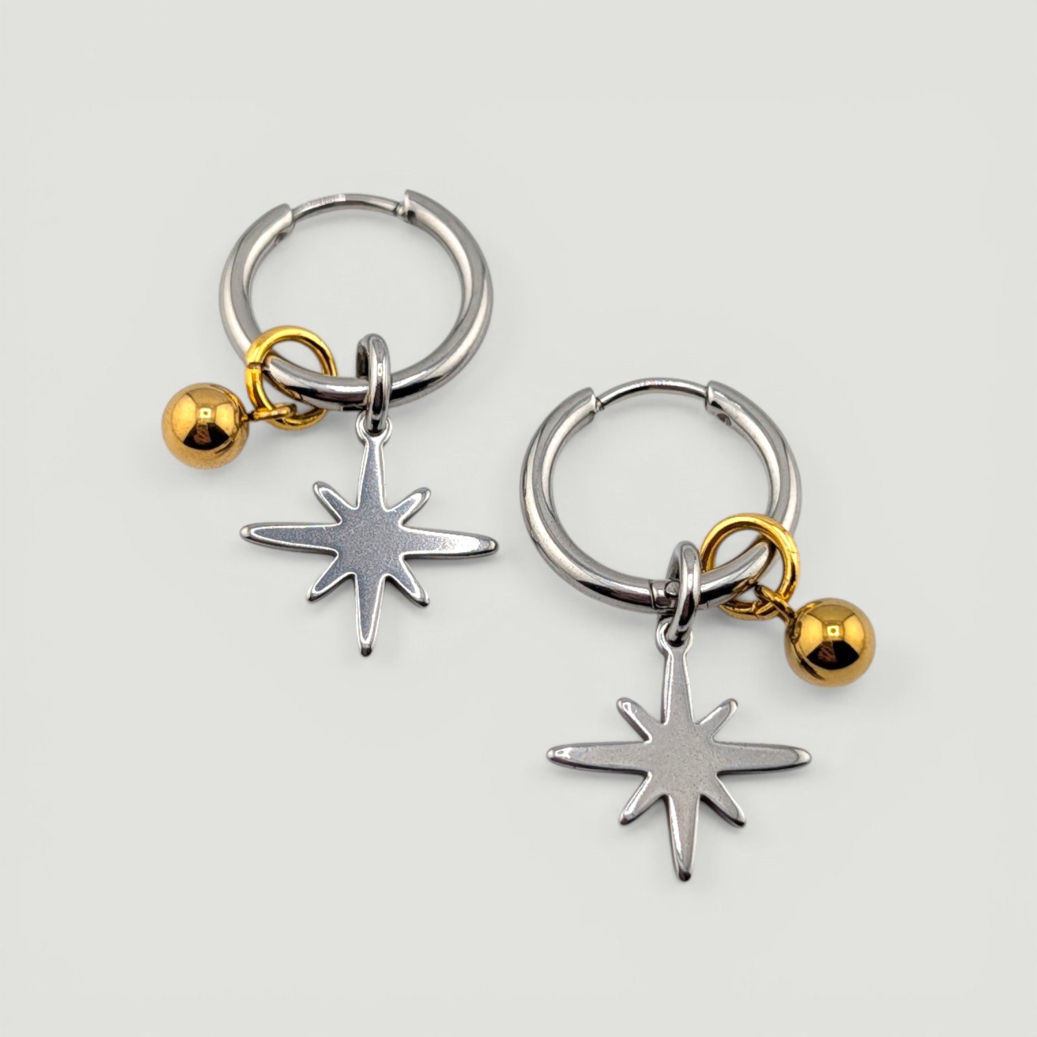 Silver northern star stainless steel huggie hoop earrings with gold bead charm flat lay