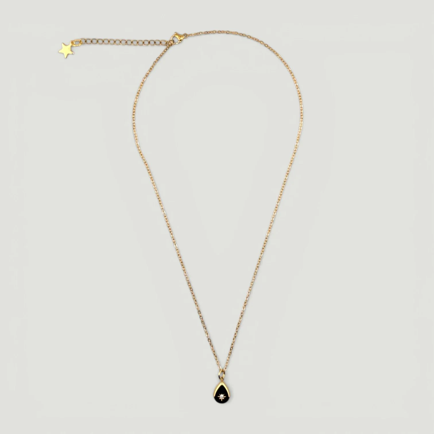 Gold stainless steel starburst teardrop necklace, full view flat lay