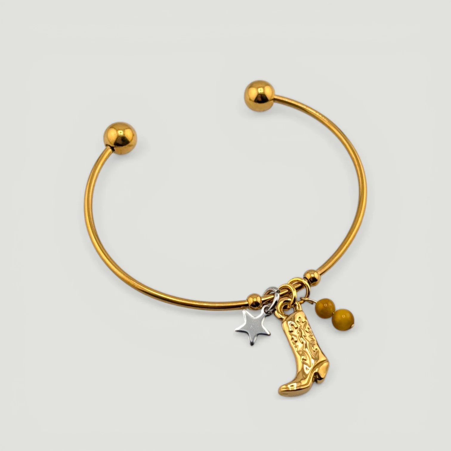 Gold cowboy boot stainless steel bangle bracelet with star and gemstone accents, full flat lay