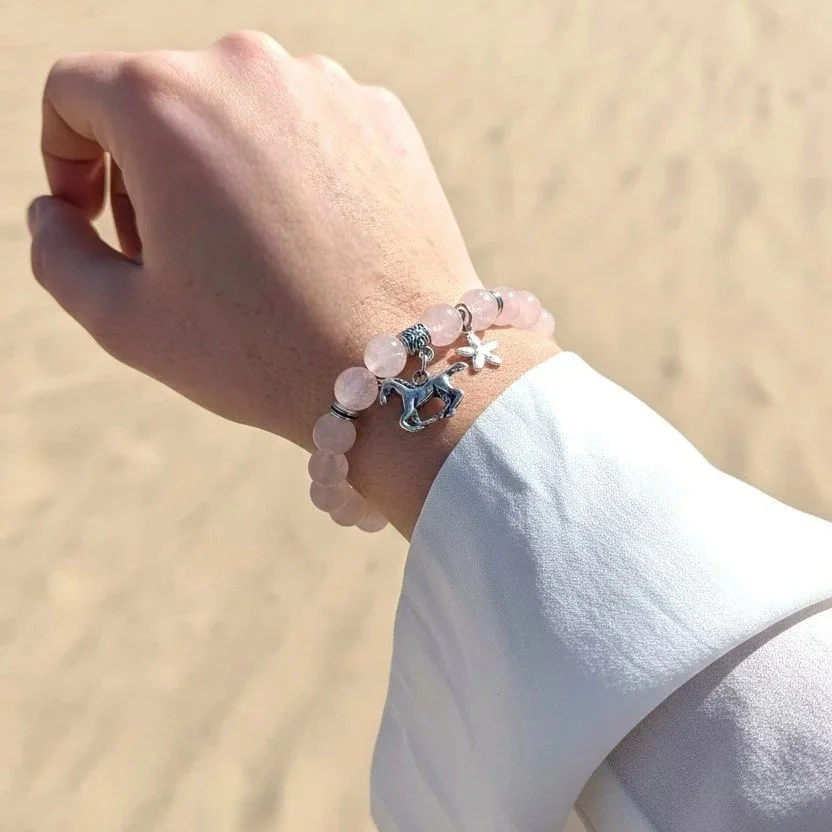 western rose quartz bracelet with a horse charms on a woman's arm with a desert background