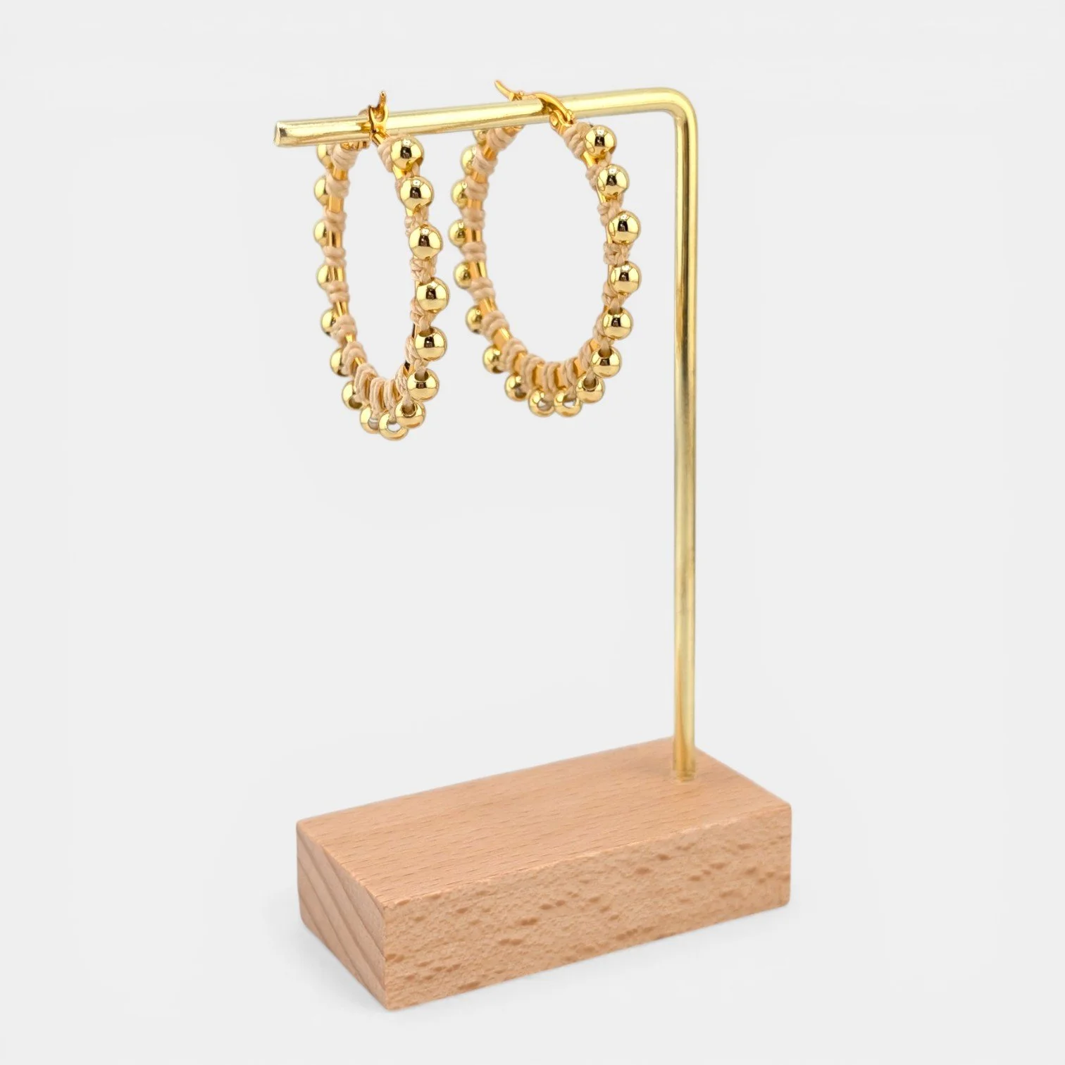 creamy beige beaded macramé stainless steel hoop earrings in gold, 40 mm drop shown on earring display stand