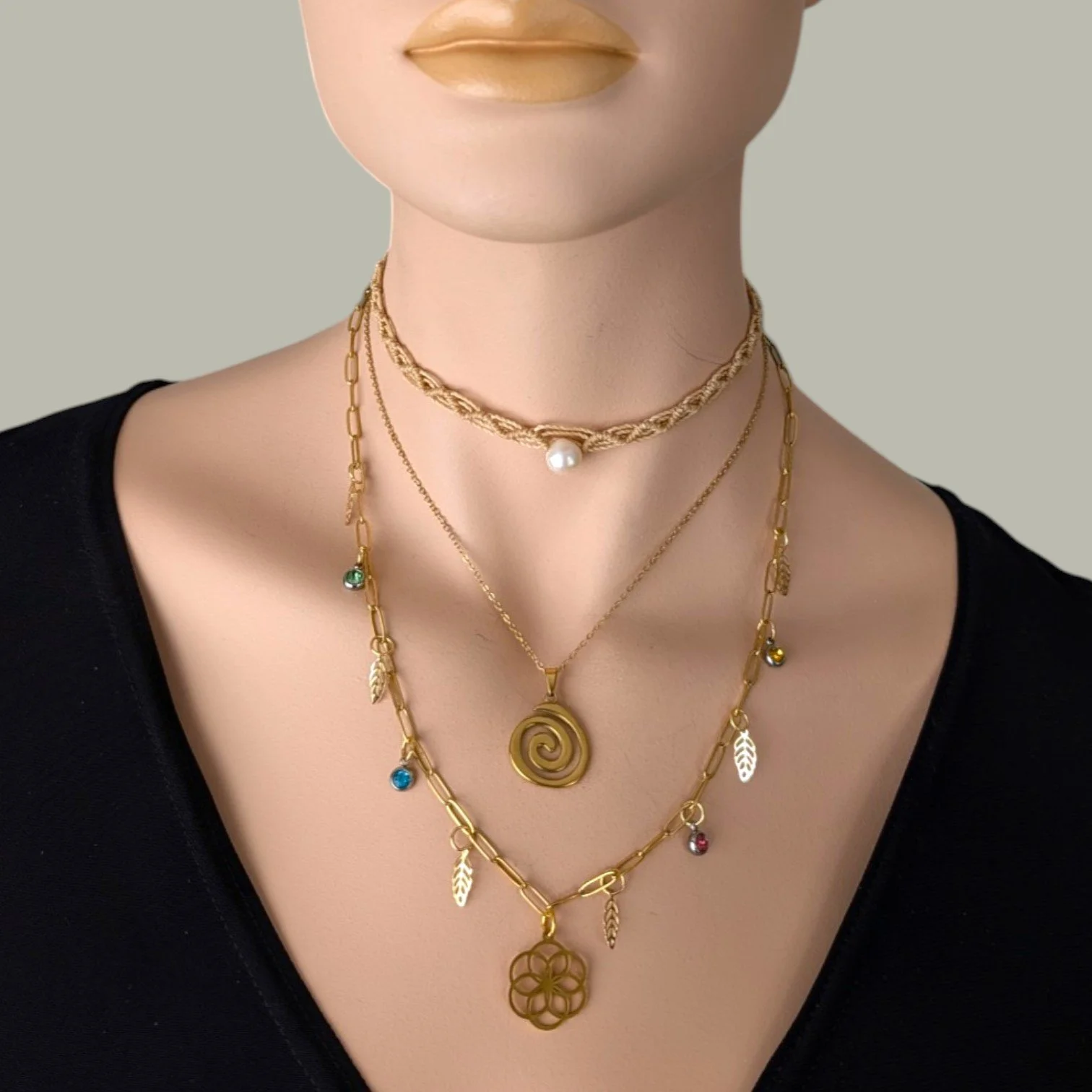 seed of life gold stainless steel paperclip charm necklace layered with macrame pearl choker and spiral necklace on mannequin bust close up