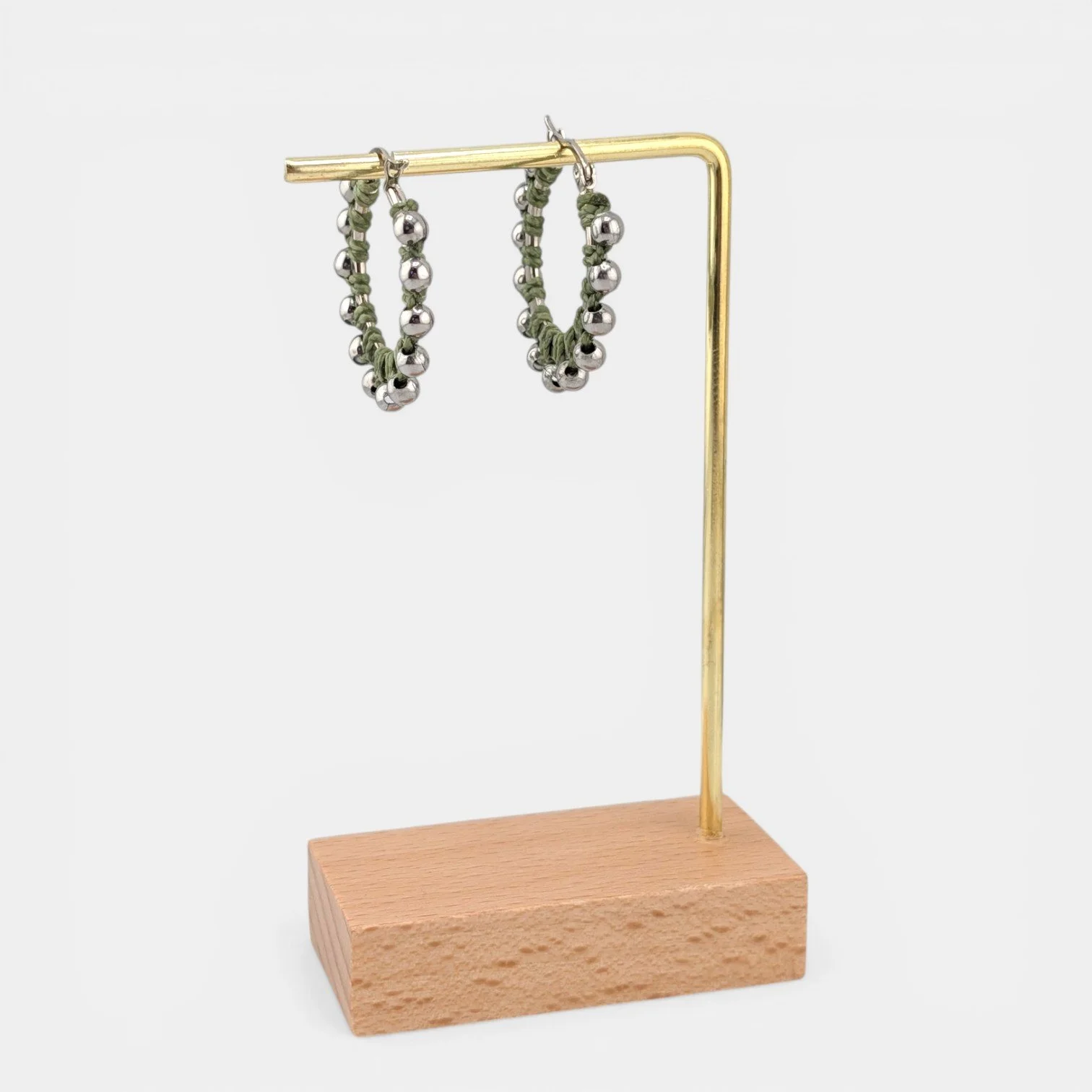 Light moss green beaded macramé stainless steel hoop earrings in silver, 30 mm drop shown on earring display stand