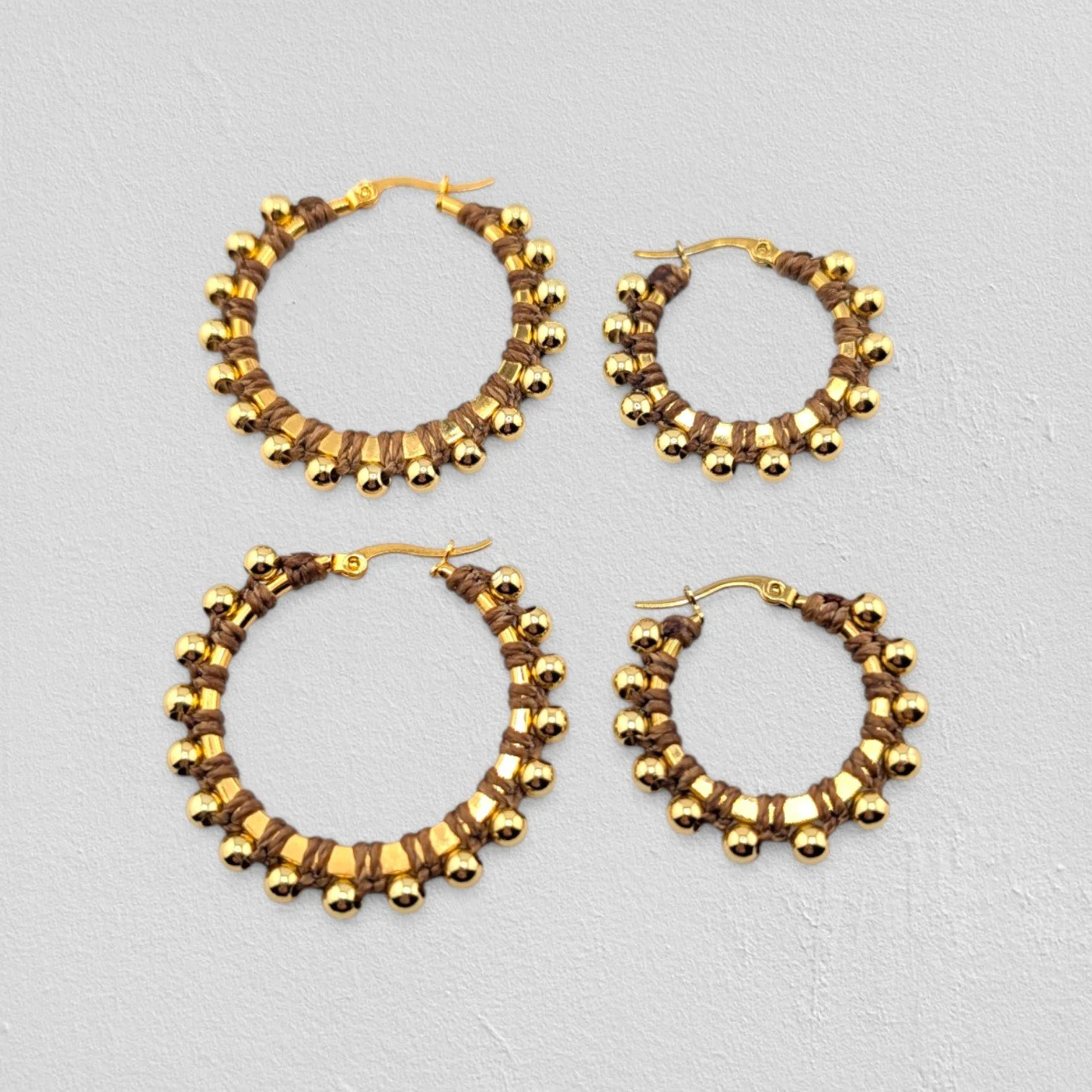 golden brown beaded macramé stainless steel hoop earrings in gold, 30 mm and 40 mm sizes side by side, flat lay on a neutral background