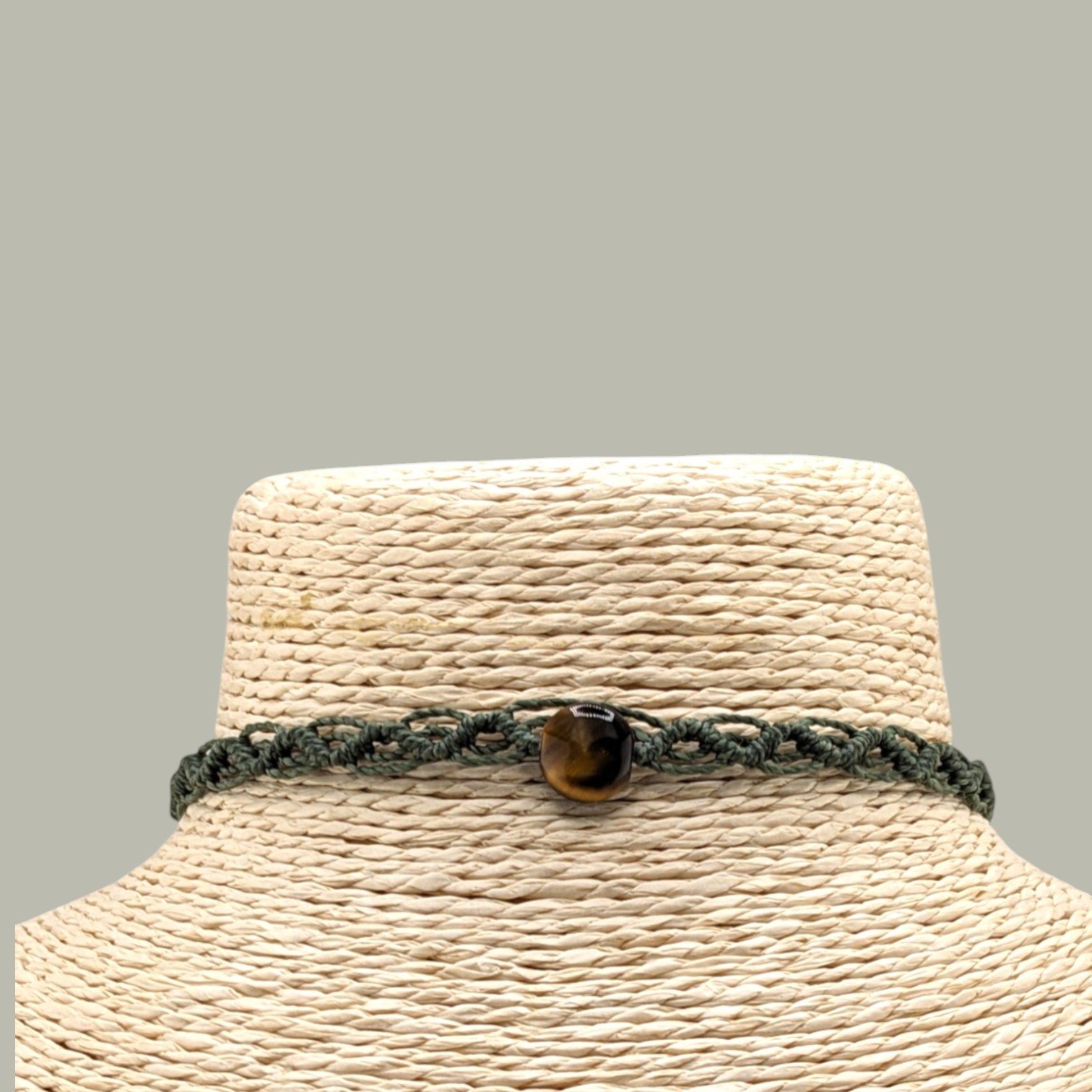 Close-up of tiger eye macrame woven choker necklace on display bust
