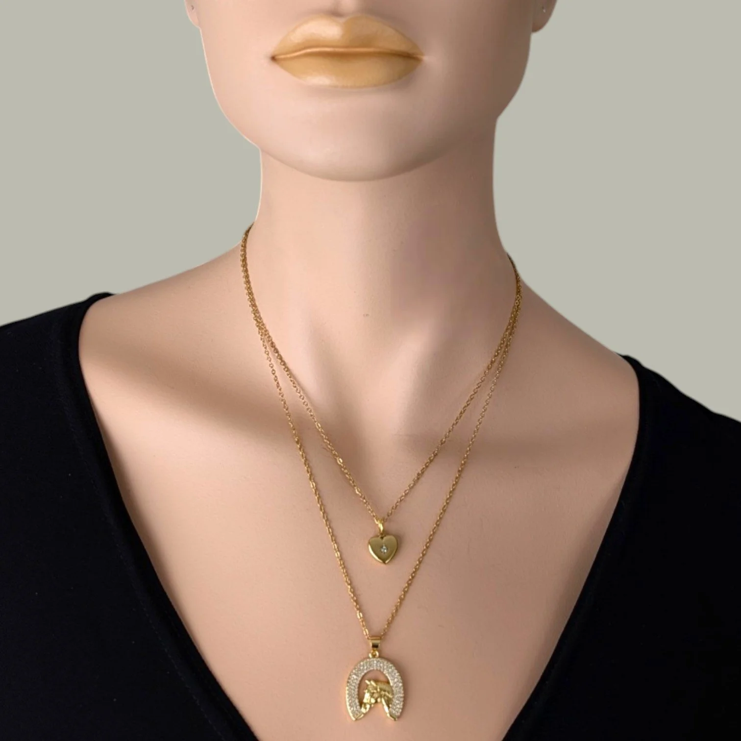 Rhinestone horseshoe horse gold stainless steel necklace layered with starburst heart necklace on mannequin, close up bust view