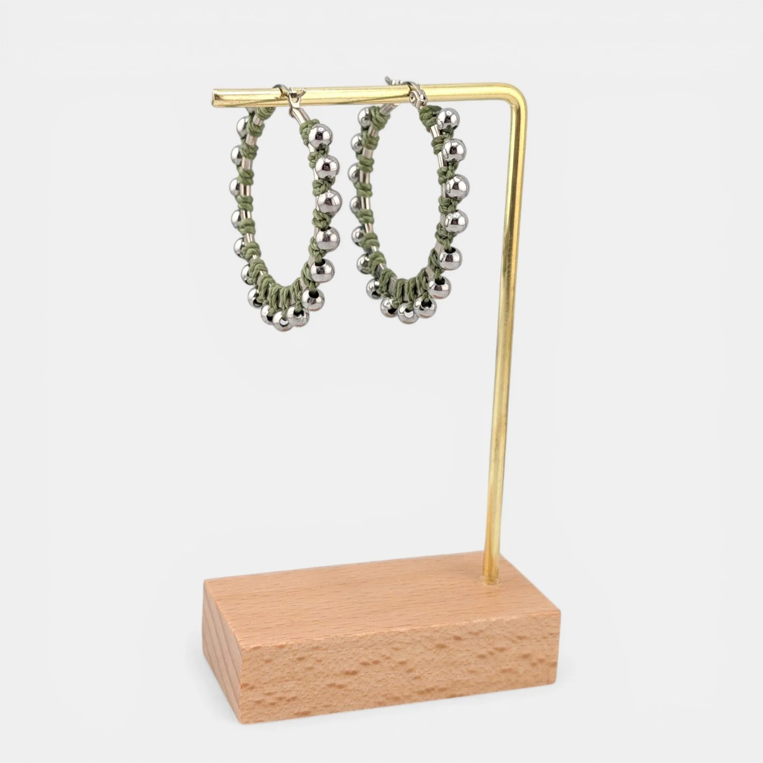 Light moss green beaded macramé stainless steel hoop earrings in silver, 40 mm drop shown on earring display stand
