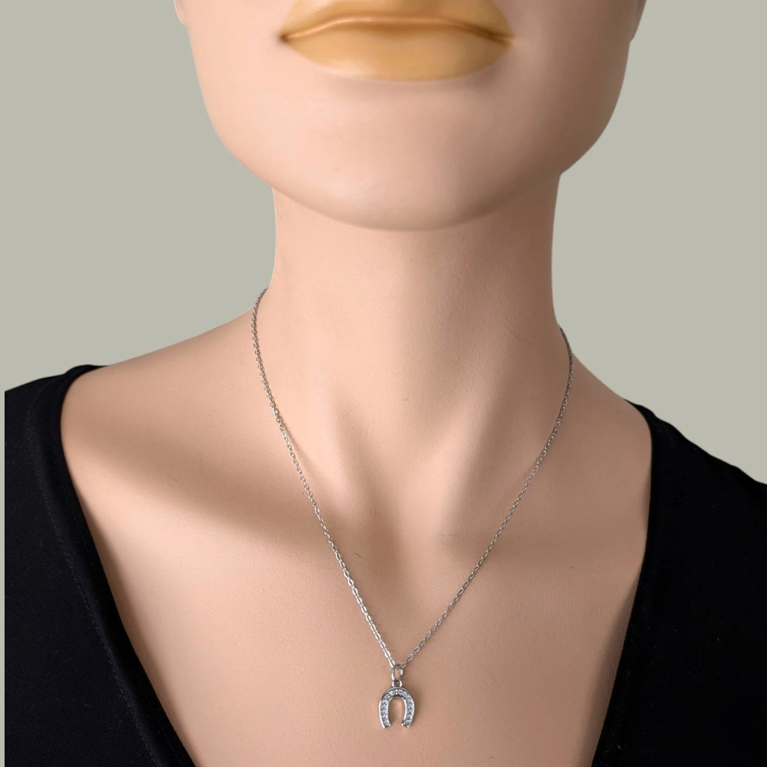 silver rhinestone horseshoe necklace on stainless steel chain worn on mannequin, close up bust view