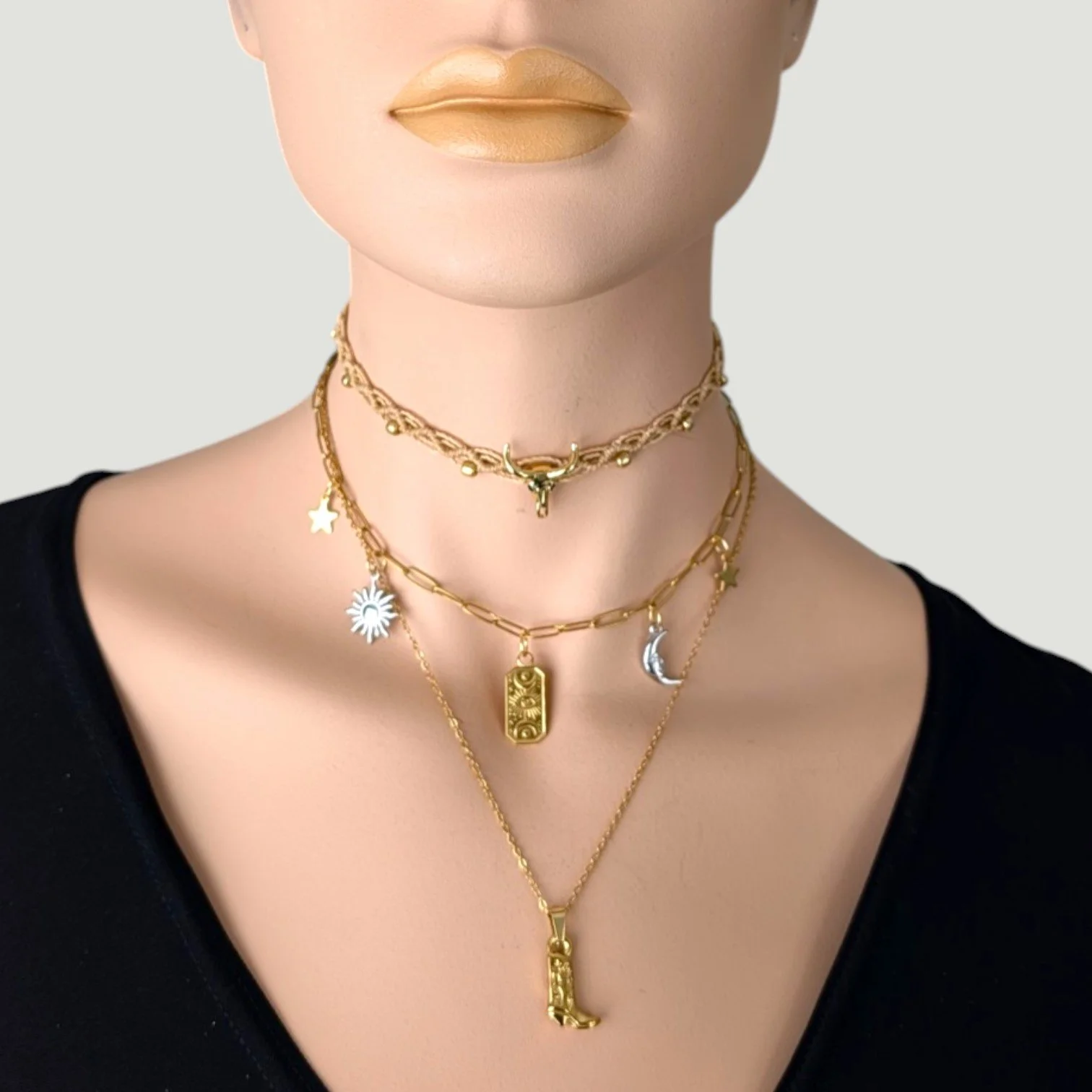 gold stainless steel cowboy boot necklace layered with bull skull choker and celestial charm necklace on mannequin, bust view