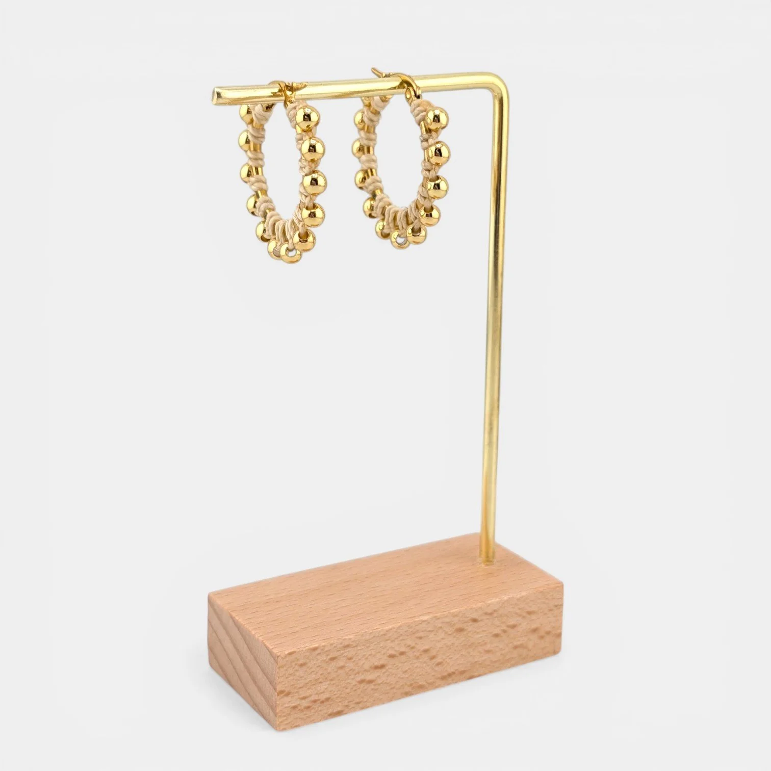 Creamy beige beaded macramé stainless steel hoop earrings in gold, 30 mm drop shown on earring display stand