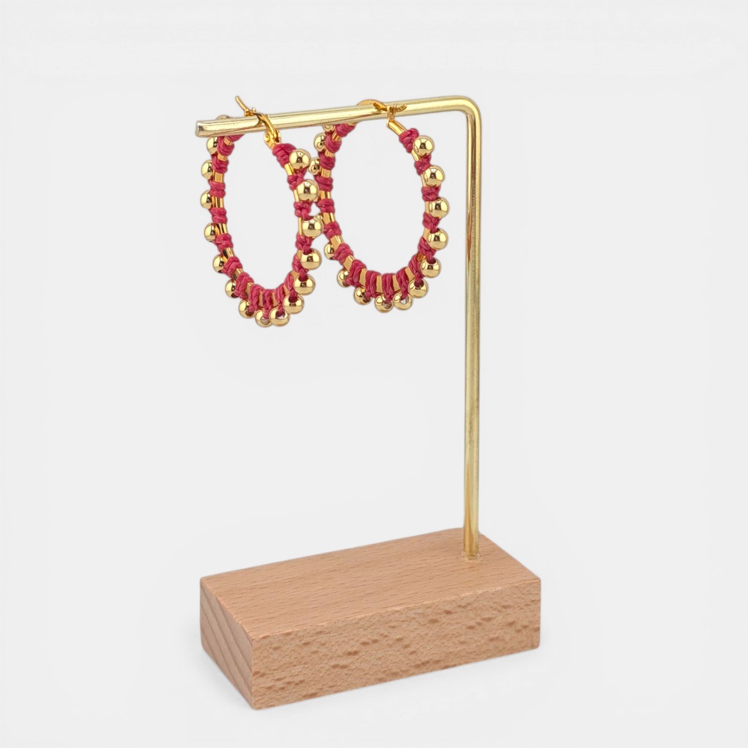 Pink beaded macramé stainless steel hoop earrings in gold, 40 mm drop shown on earring display stand