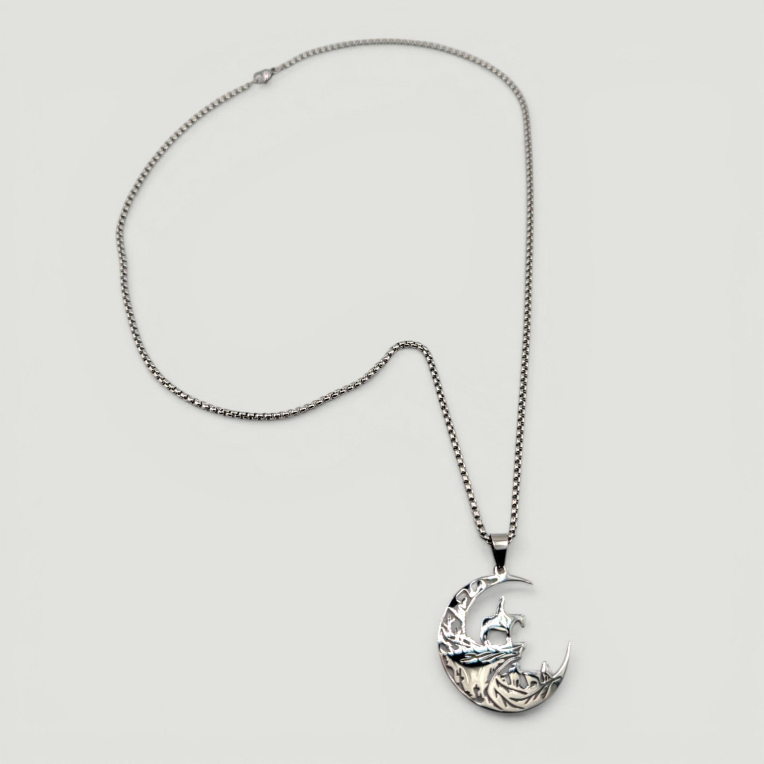 full view flat lay of men's cowboy moon stainless steel necklace showing chain and pendant