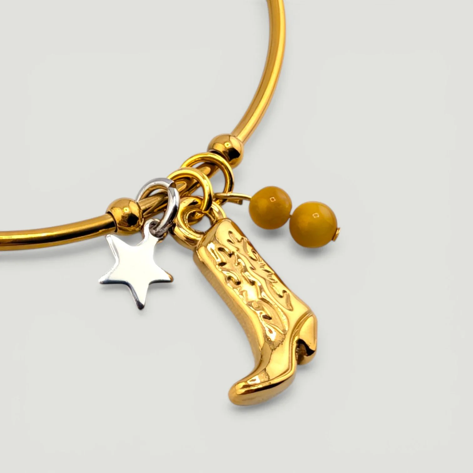 Gold cowboy boot stainless steel bangle bracelet with star and gemstone accents, close-up