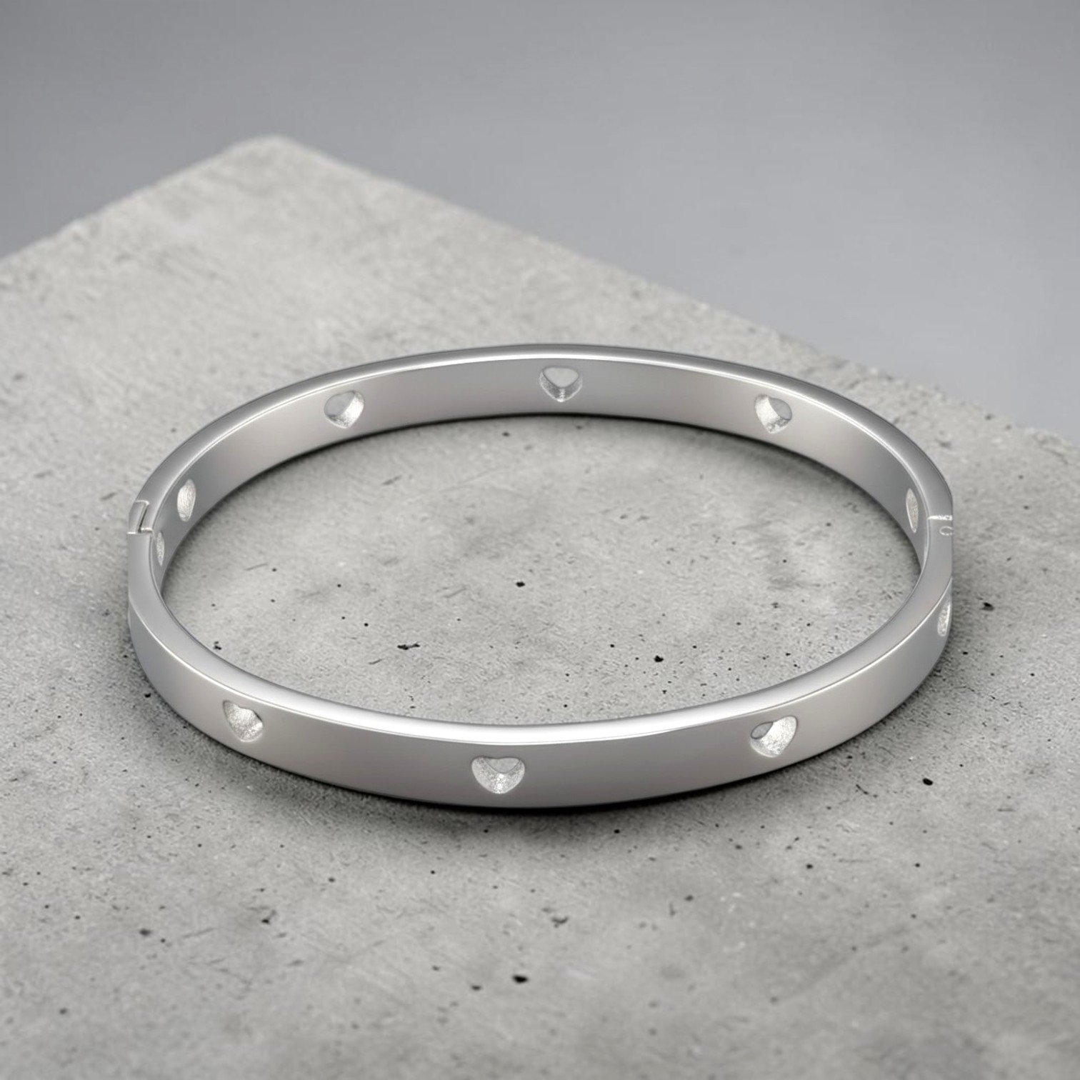 Silver hollow heart stainless steel bangle bracelet, angled flat lay