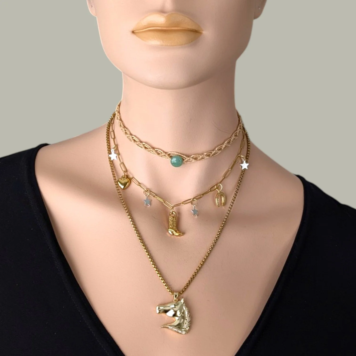 Rhinestone horse necklace on gold stainless steel chain layered with aventurine macrame choker and cowboy boot charm necklace on mannequin, close up bust view