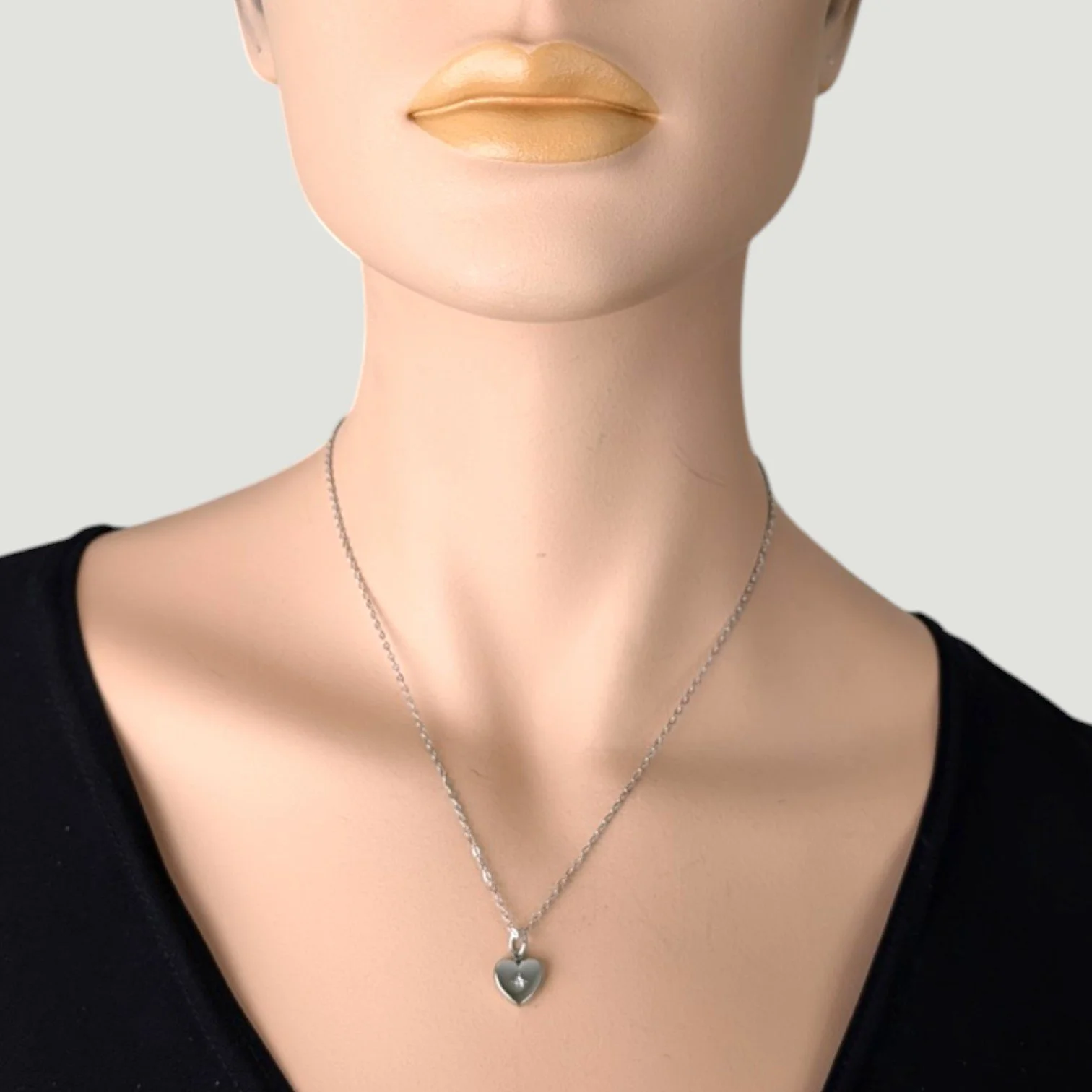 Silver stainless steel starburst heart necklace on mannequin, close up bust view