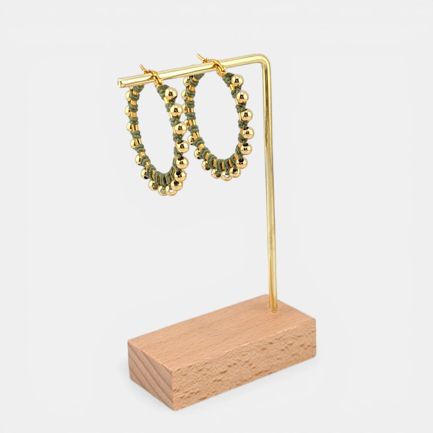 Light moss green beaded macramé stainless steel hoop earrings in gold, 40 mm drop shown on earring display stand