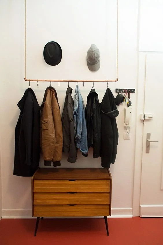 Ausstattung im Flur mit einer Hakenleiste mit Jacken, Mützen, einer Wandlampe, einem Schlüsselhaken und einem kleinen Kommode