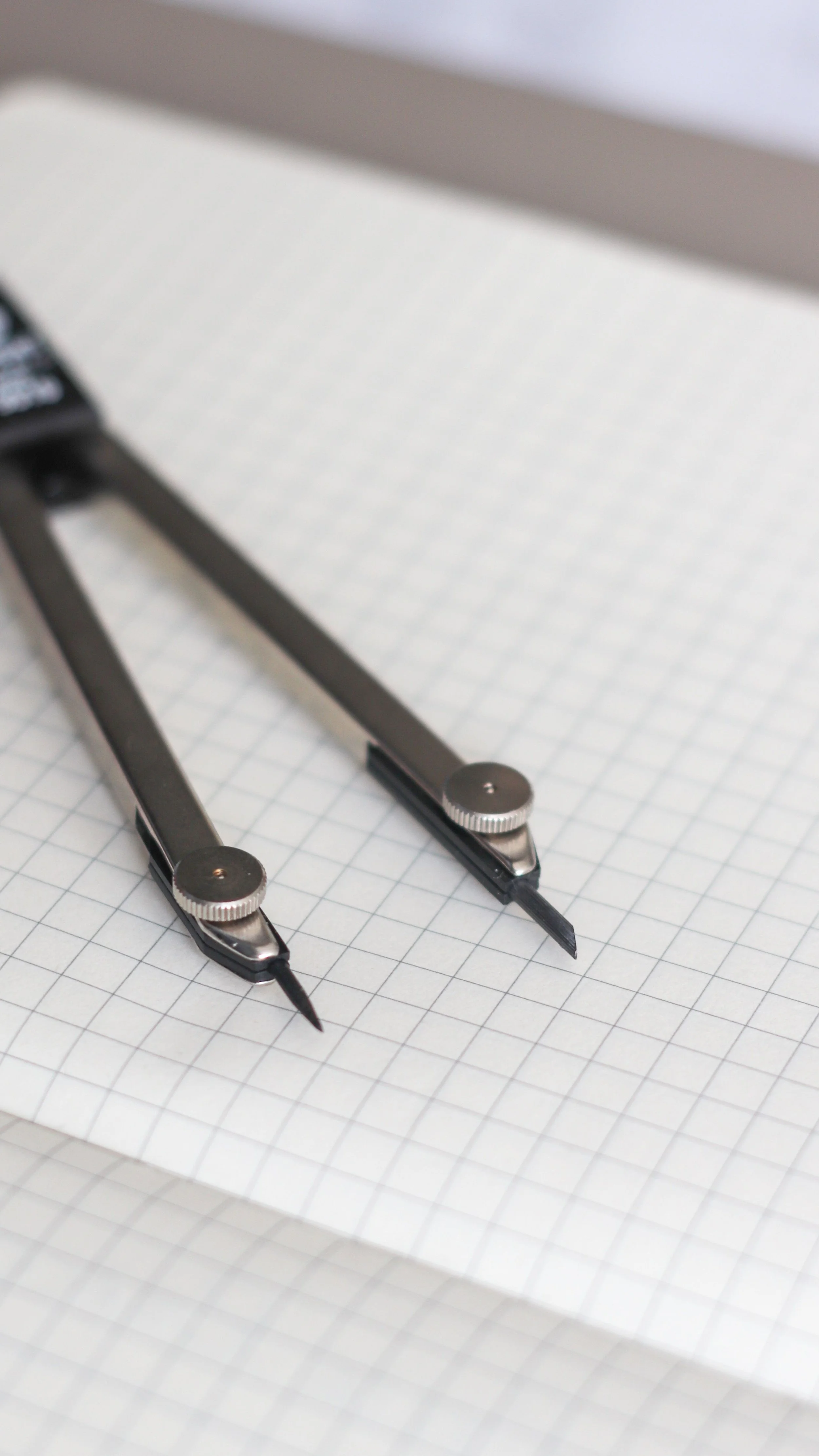 A metal compass on a sheet of graph paper. science writing