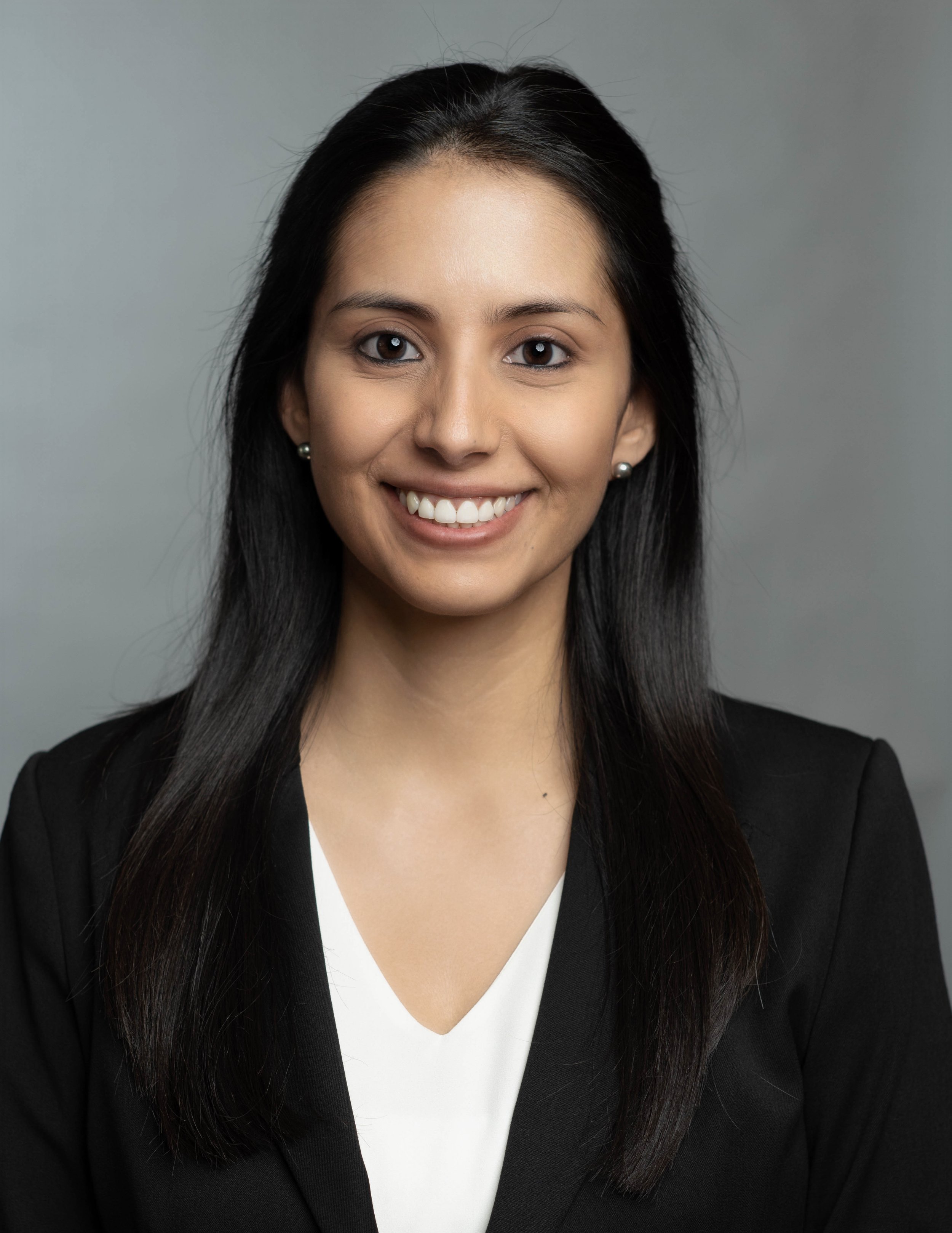A professional woman with long black hair in a business suit, smiling at the camera.