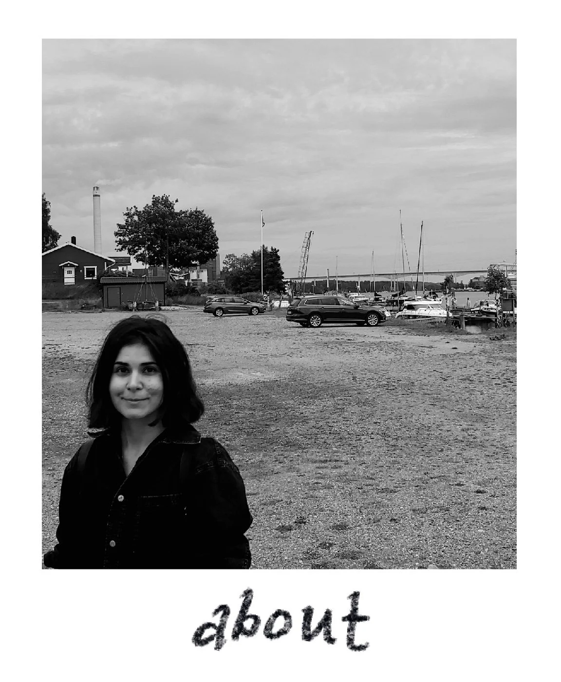 A black and white photo of a young woman with shoulder-length dark hair, standing outdoors near a marina with boats and parked cars. The background includes a cloudy sky, trees, a bridge, and industrial structures, with the word 'about' written at the bottom of the image.