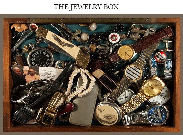 A wooden box filled with various jewelry and watches, including wristwatches, necklaces, bracelets, and rings.