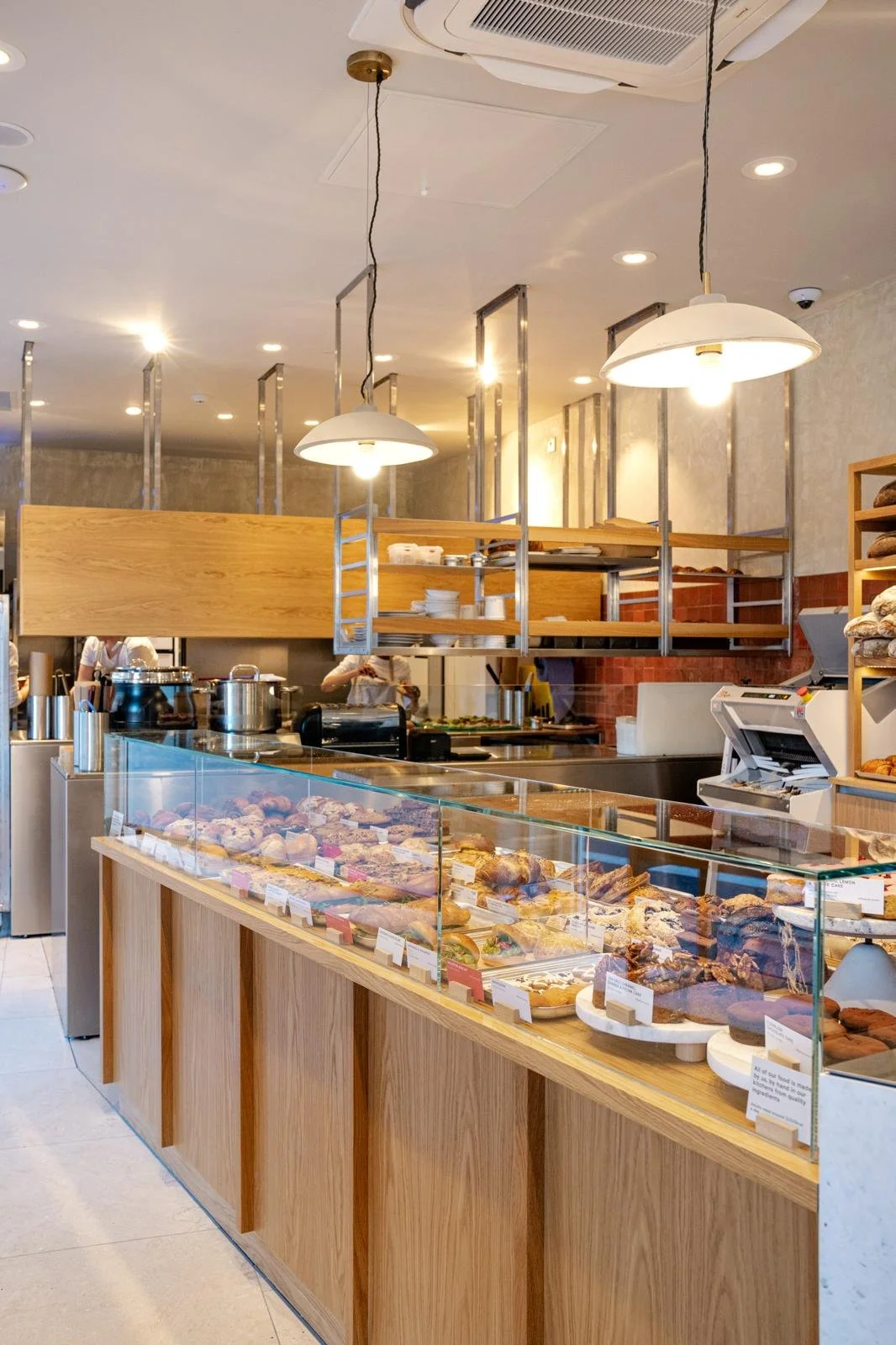 Display counter with a variety of baked goods in a bakery or cafe, featuring a glass case and wooden accents.