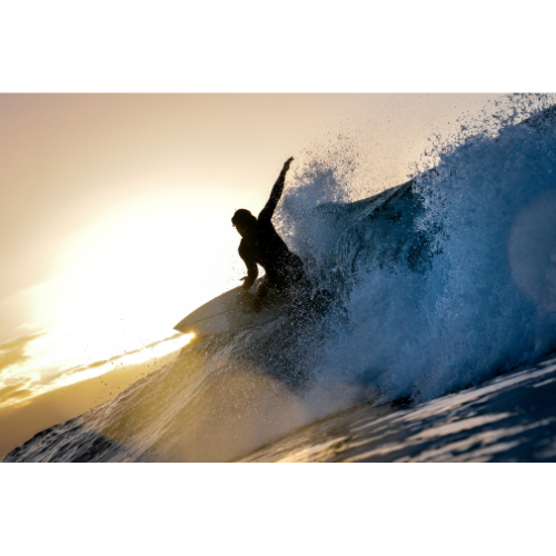 Un surfeur sur une vague au coucher du soleil.