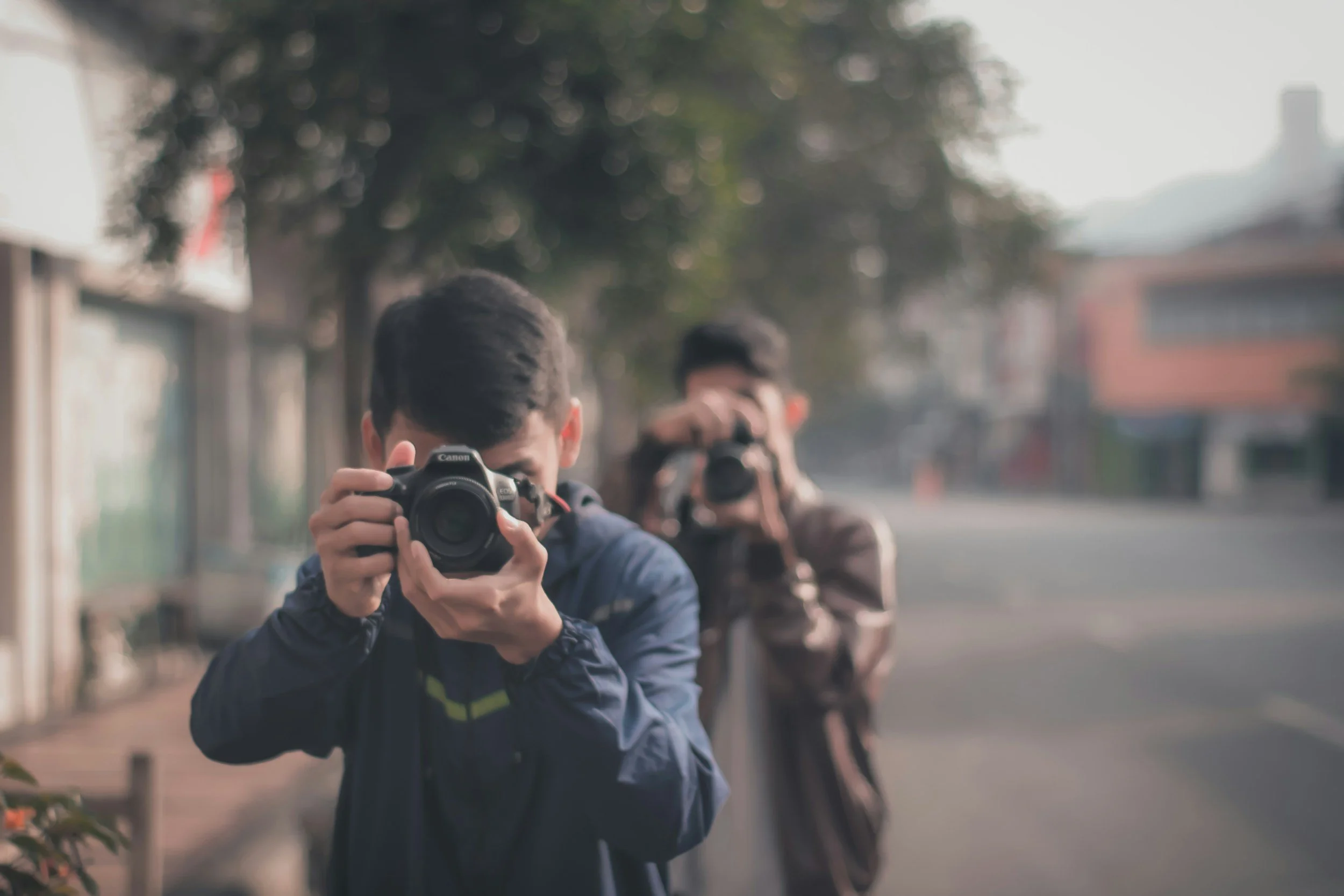 Deux jeunes hommes prennent une photo avec leurs appareils photo dans une rue urbaine