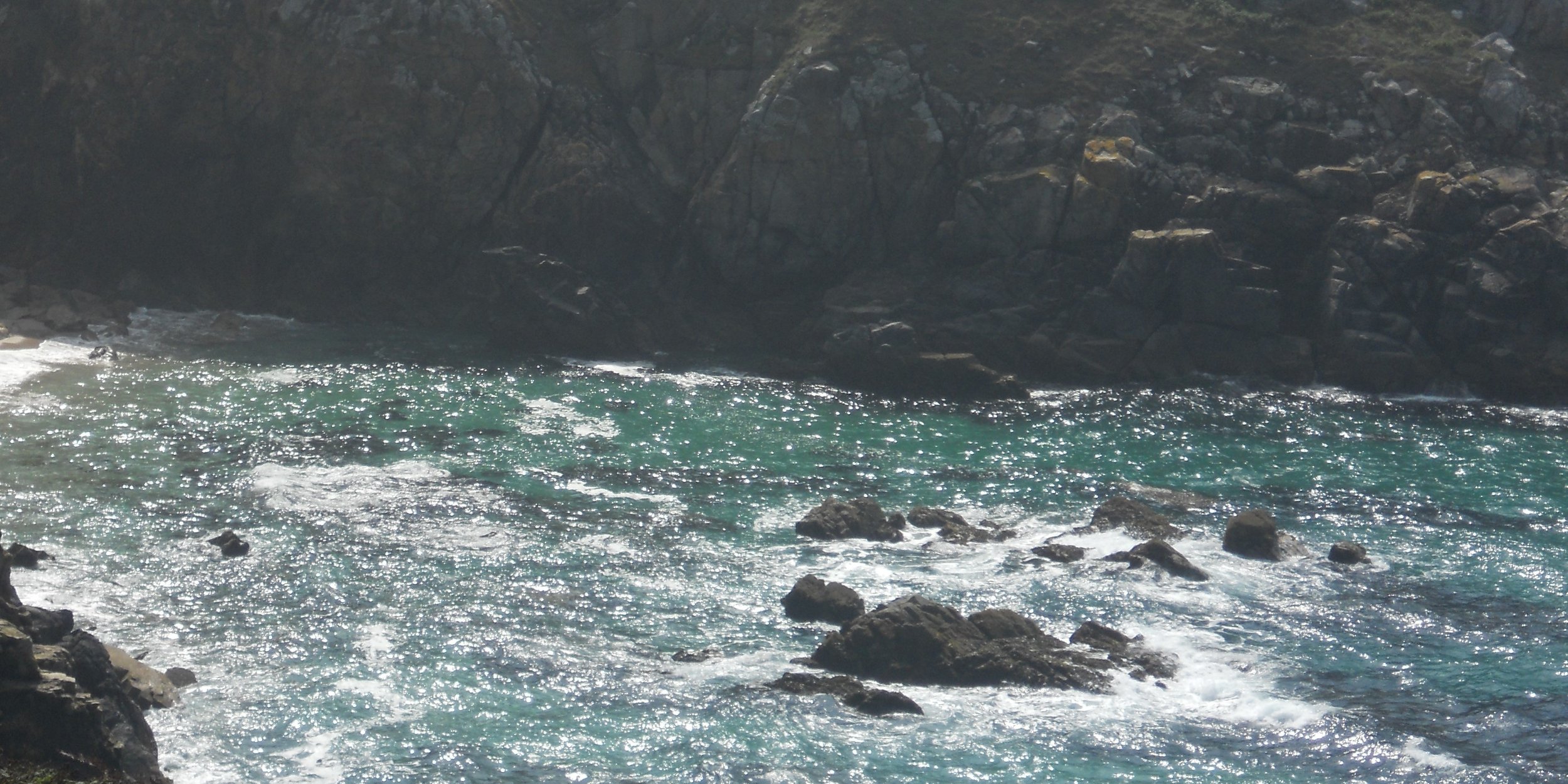 Mer agitée avec vagues au bord de rochers escarpés sous le ciel lumineux de la Mer d'Iroise.