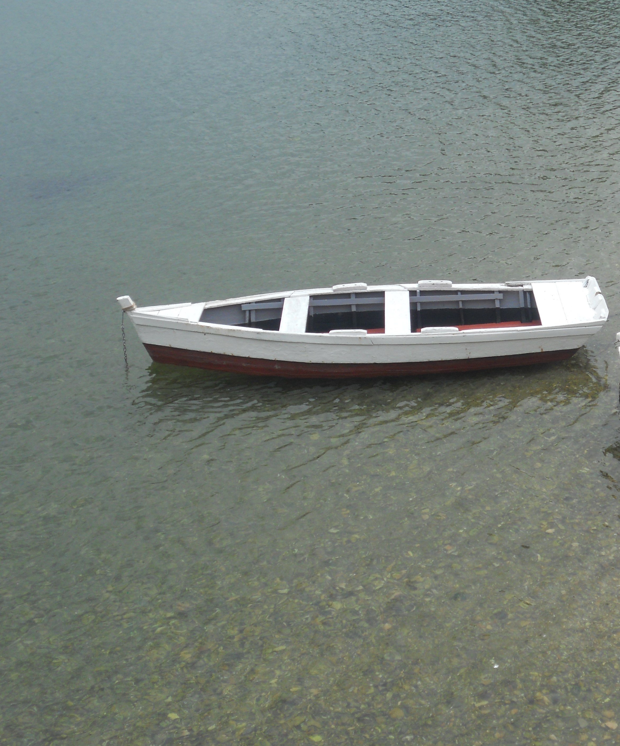Un petit bateau blanc flotte sur une eau calme et claire
