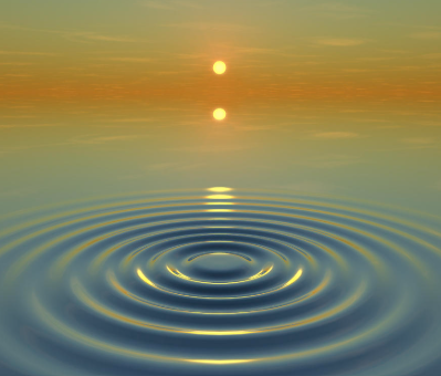 Sunset over a calm body of water with a reflection of the sun and ripples on the surface.