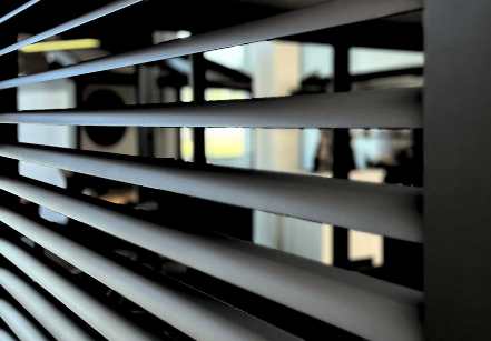 Close-up of horizontal window blinds with light filtering through.