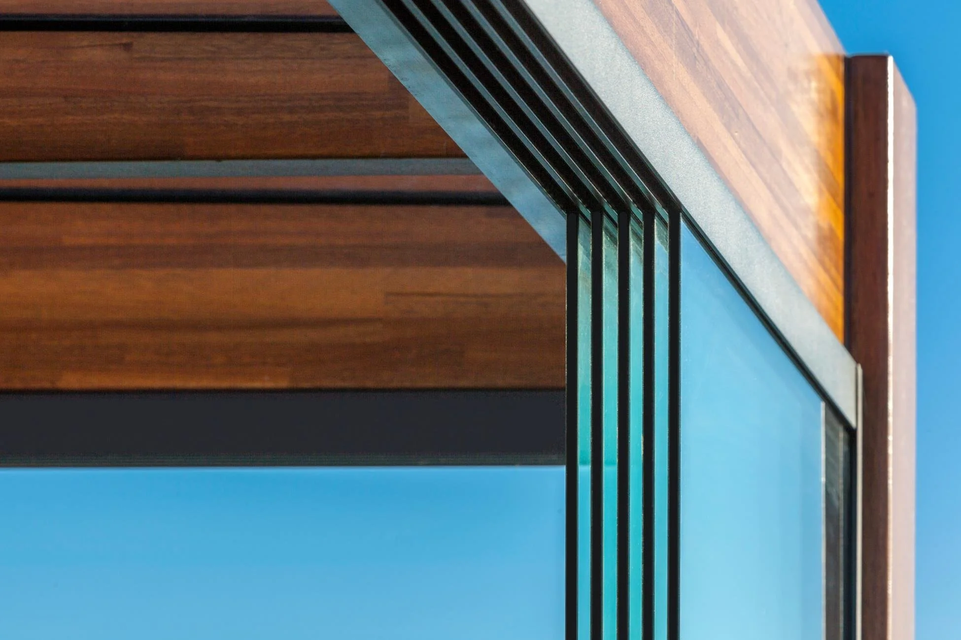 Close-up of a modern wooden and metal table edge with a blue background.