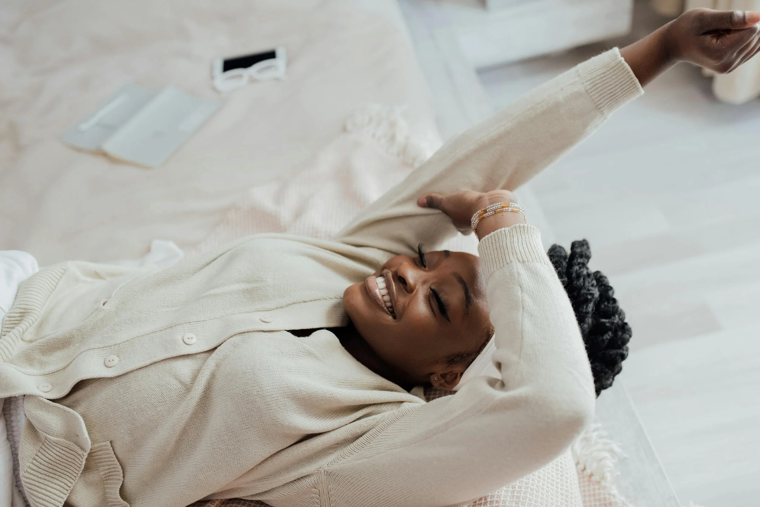 Woman resting on a bed with eyes closed, representing recovery, rest, and restoring well-being after exhaustion.