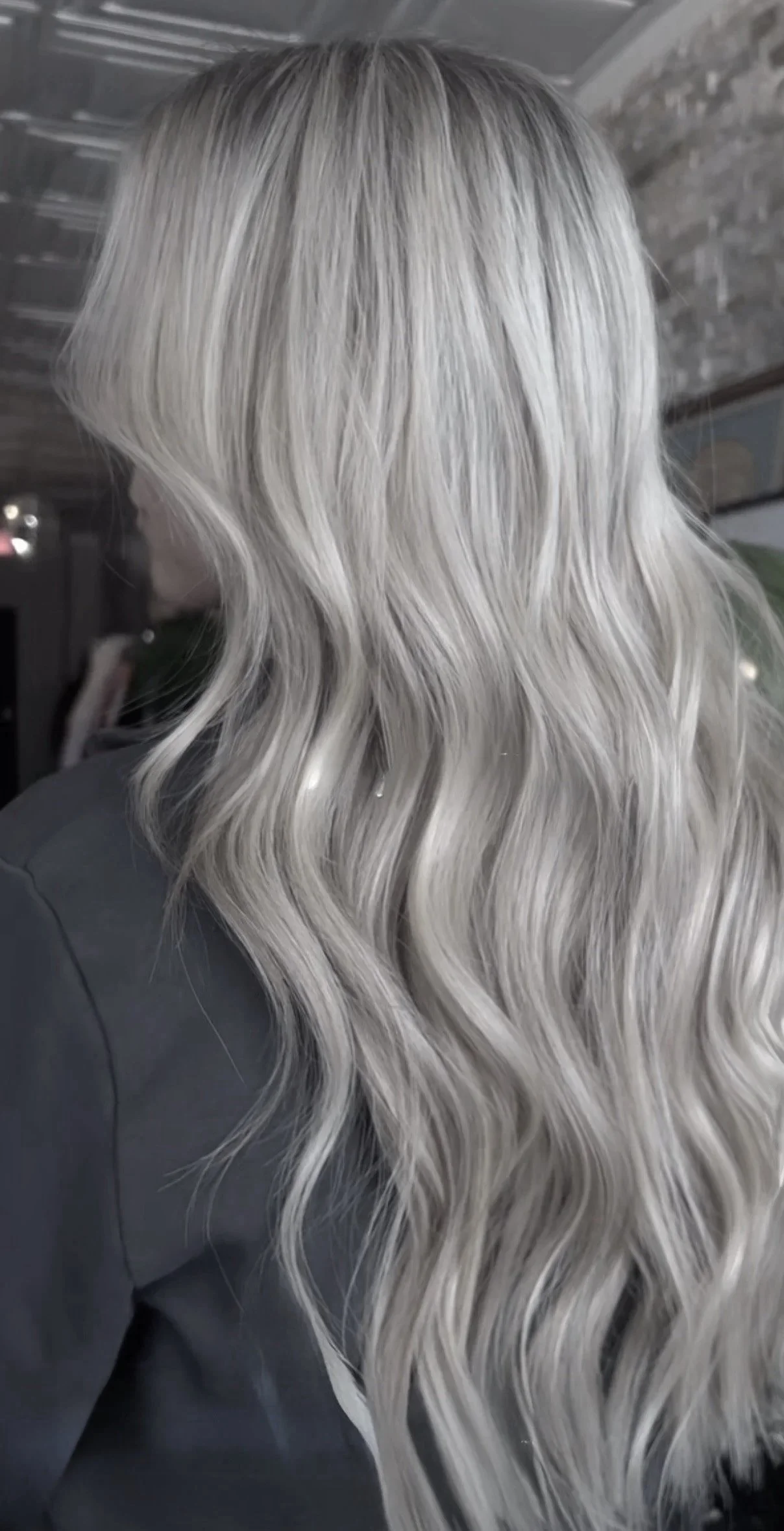 Back of a woman with long, wavy, platinum blonde hair.