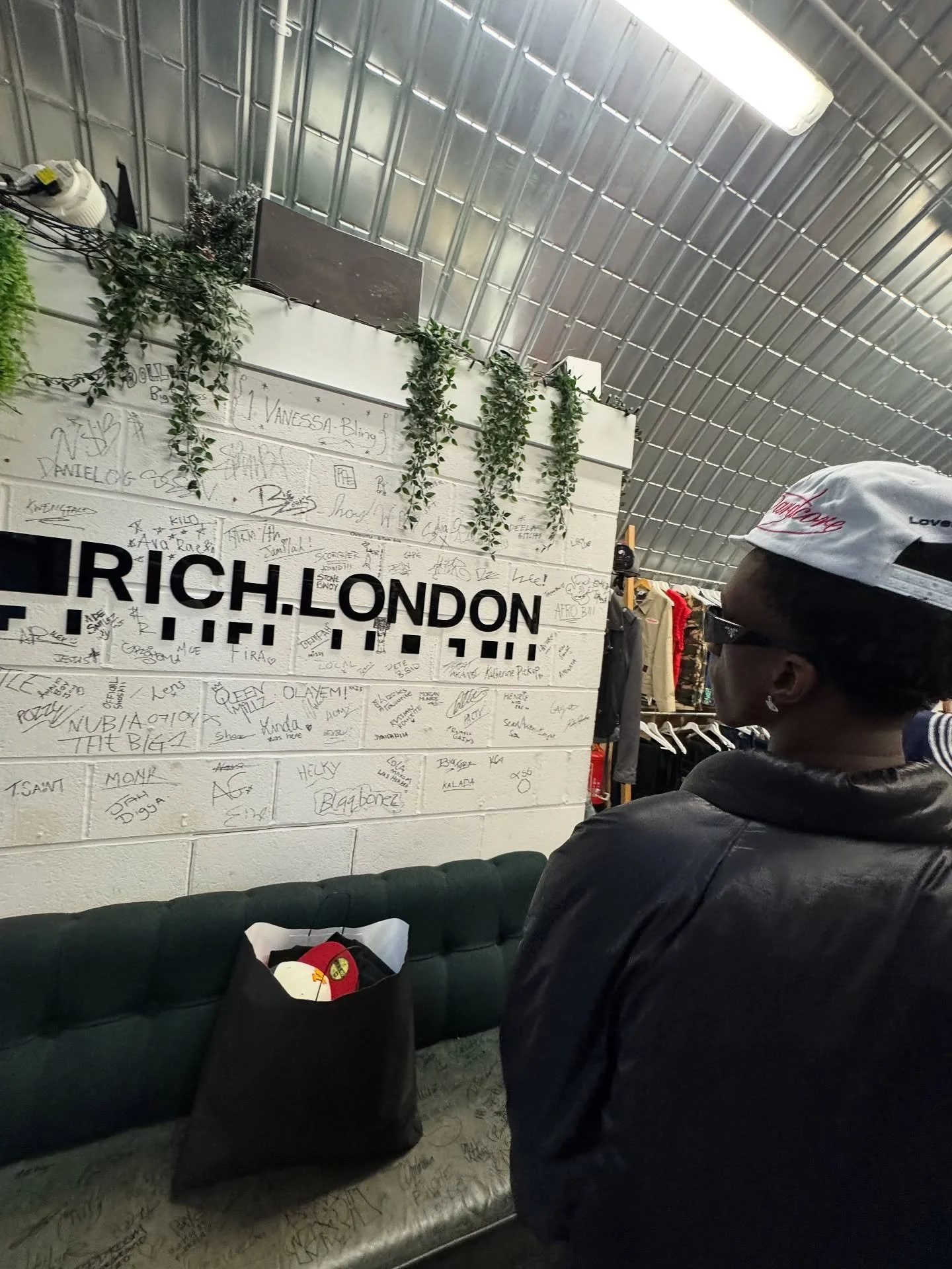 Mavo standing in front of a hoodie store. That wall has many handwritten signatures.