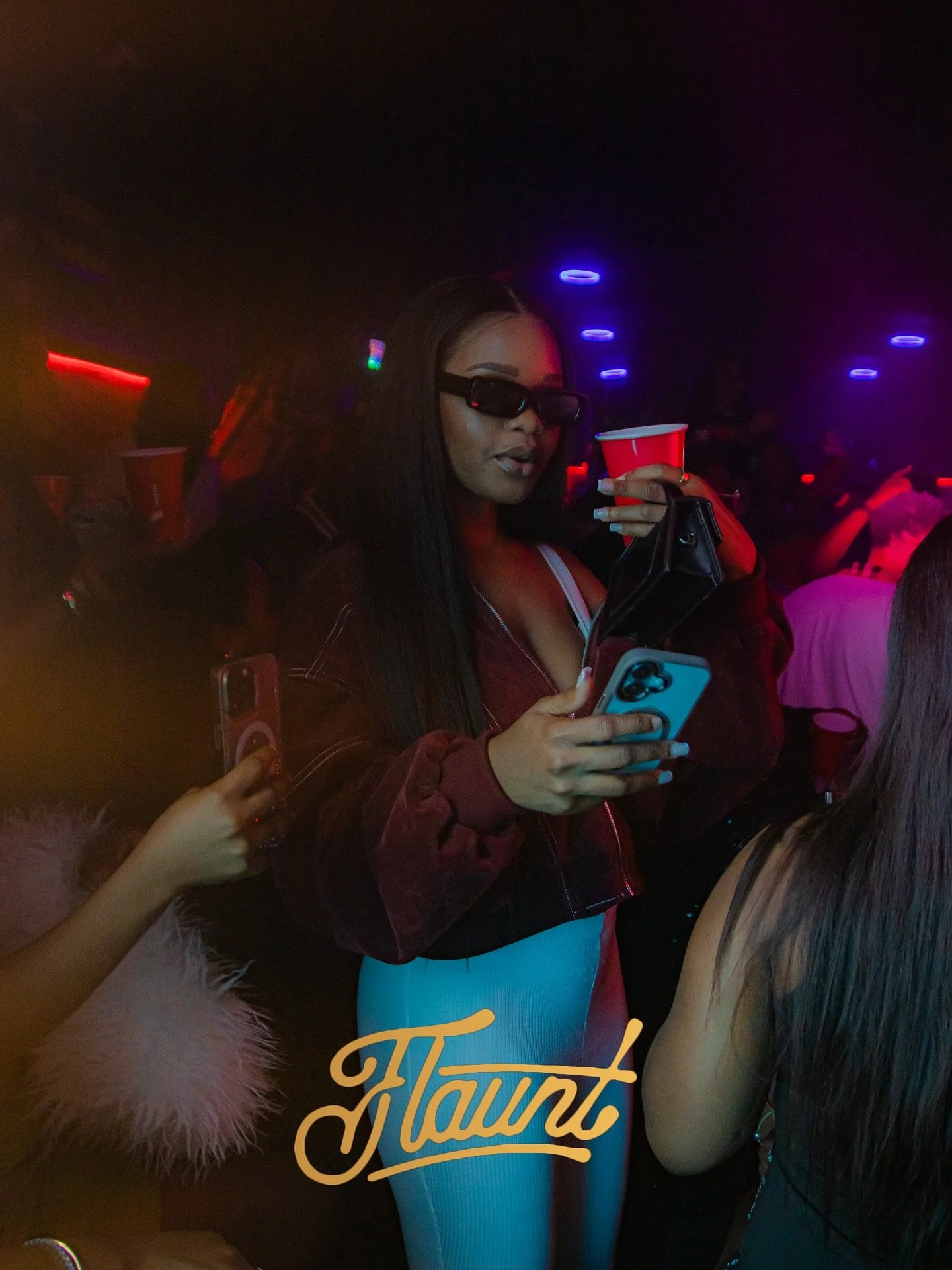 A woman wearing sunglasses, a maroon jacket, and a white top at a flaunt night