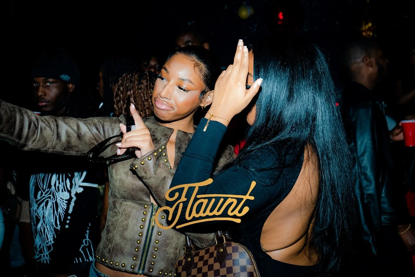 Two exquisite ladies dancing closely at a party, one with long black hair and the other with short hair. 