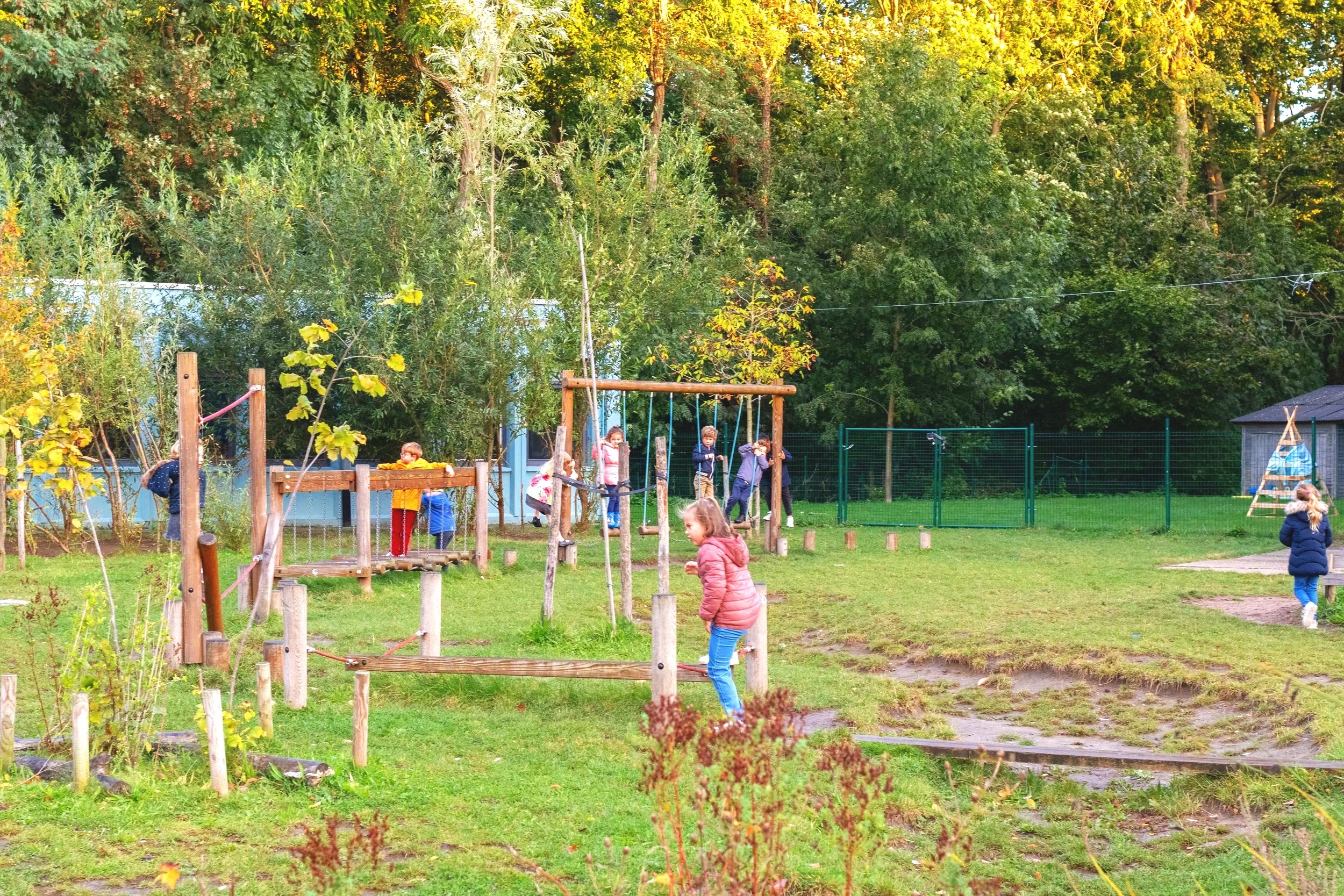 Vier lachende kinderen met rugzakken in een schoolgebouw, klaar voor de klas.
