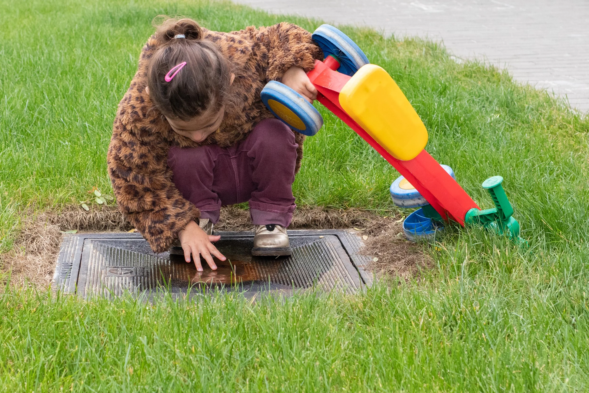 Vijf kinderen lopen in een park in de zon, omgeven door groen en bomen, lachend en vrolijk.