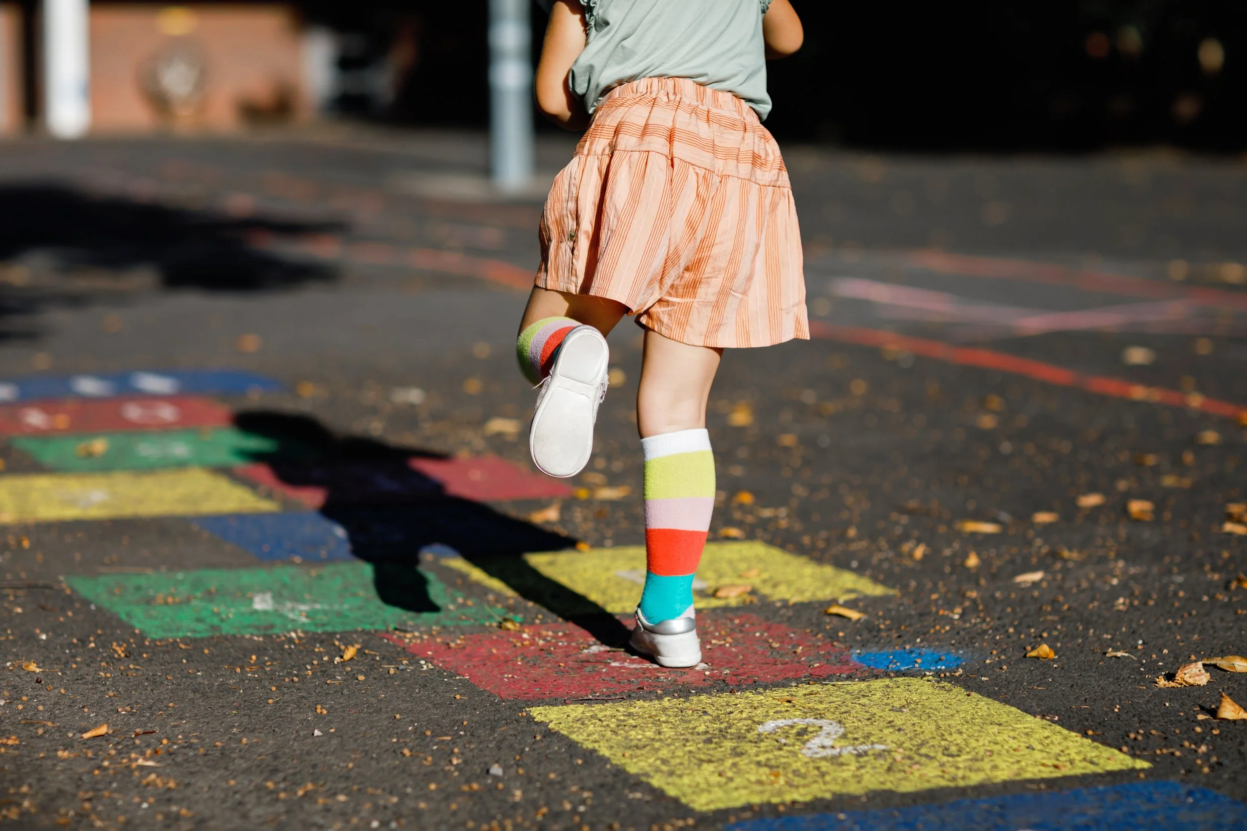 Drie lachende kinderen buiten, met een groene achtergrond.