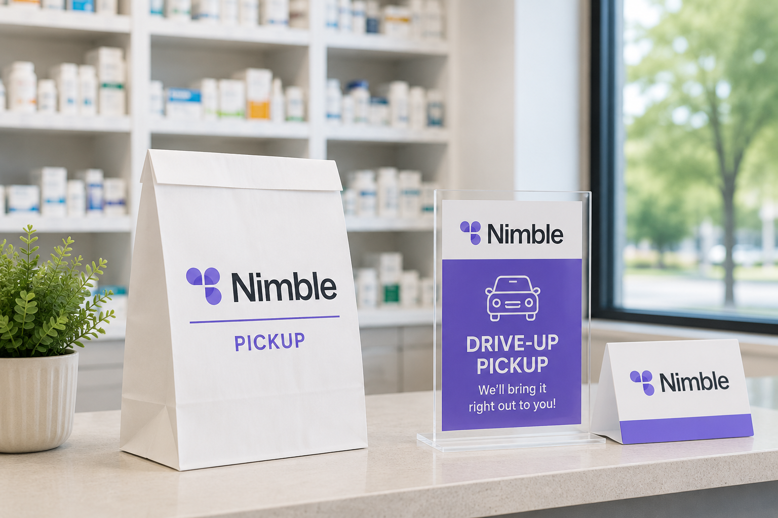 Nimble pharmacy counter with pickup bags and signs for drive-up pickup, a potted plant, and pharmacy shelves in the background.