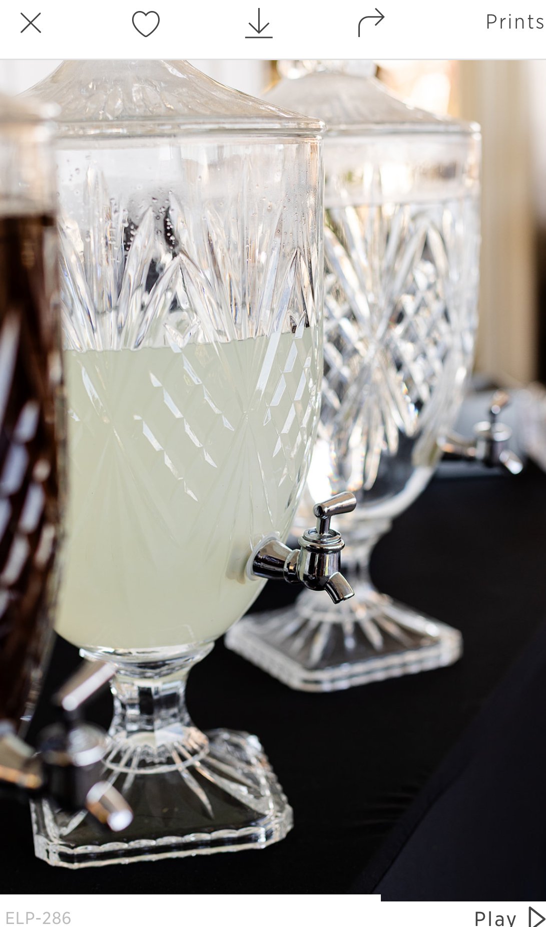 Crystal beverage dispensers filled with light-colored drinks, placed on a black table.