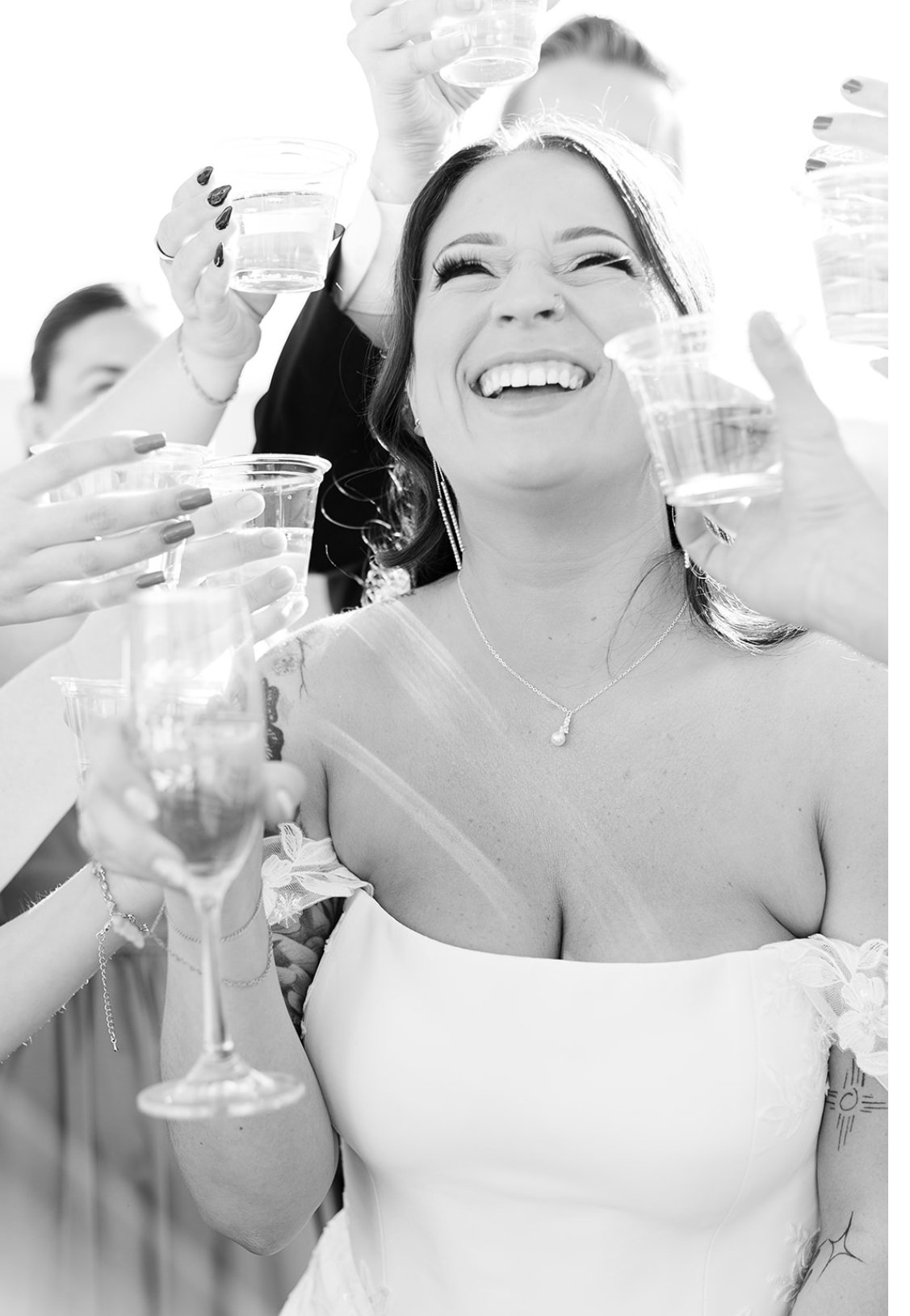 A woman in a wedding dress holding a glass of champagne, smiling and celebrating with friends.