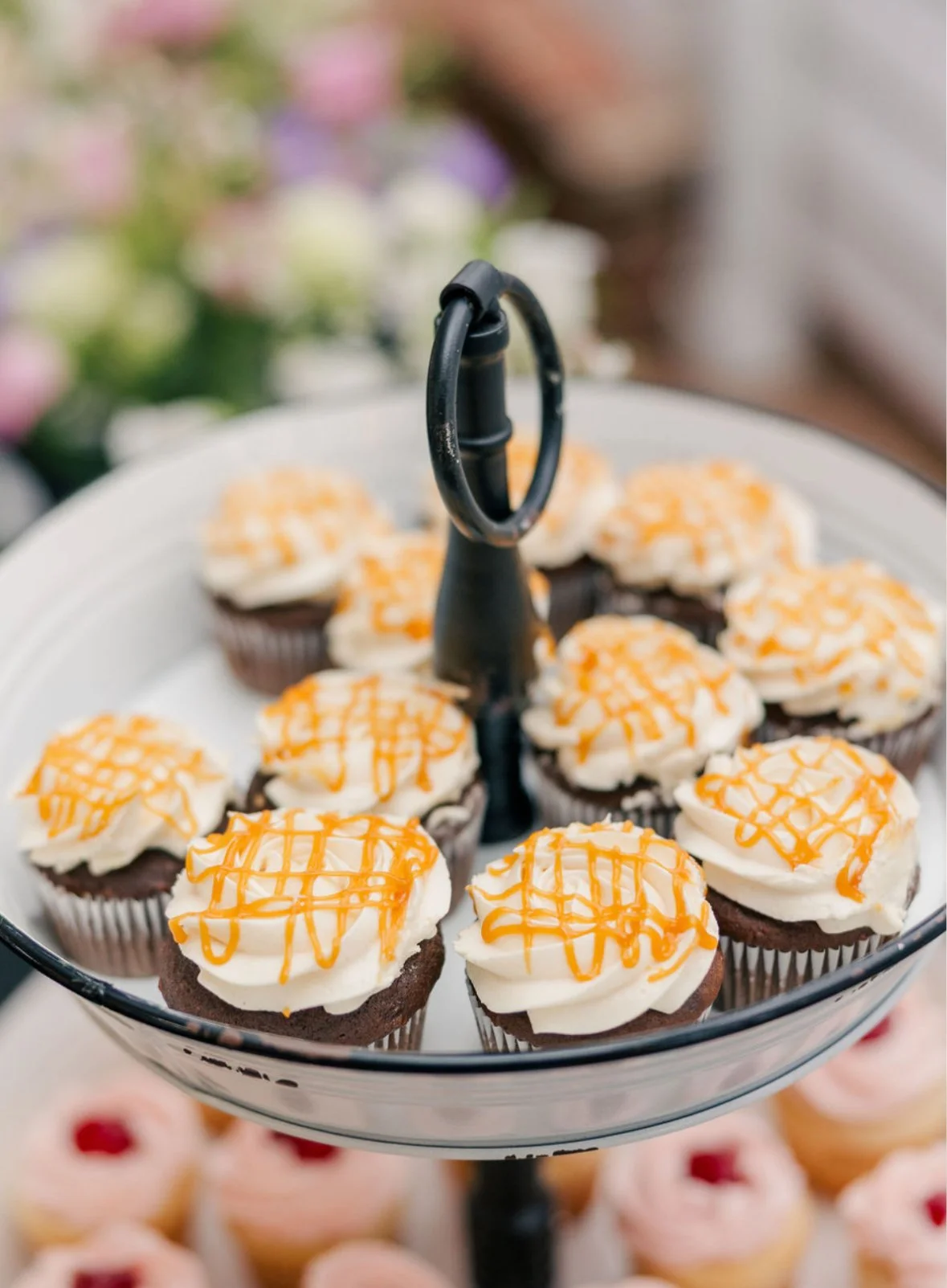 Cupcakes with orange and white icing on a tiered serving tray.